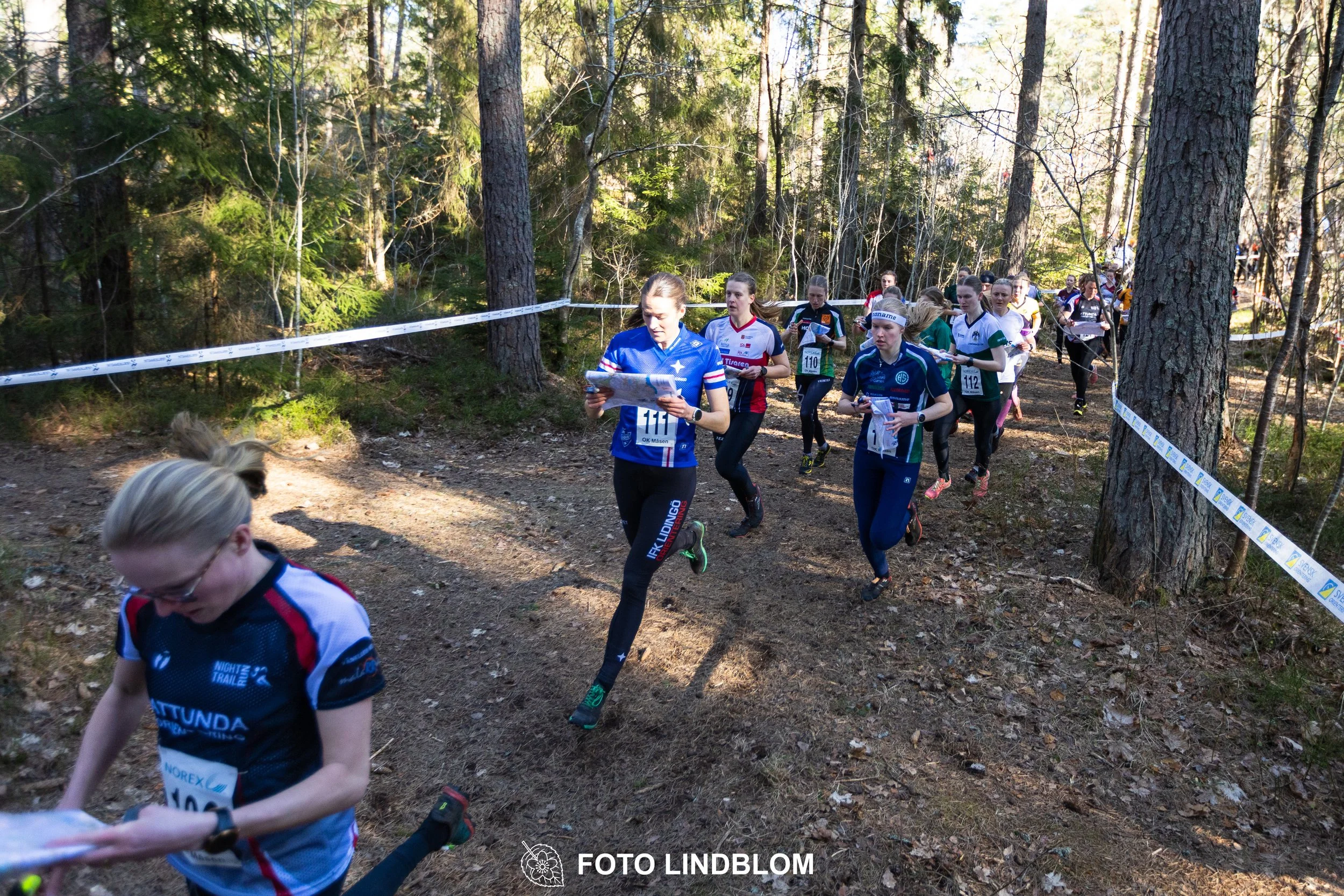 Forest relay orienteering at Måsenstafetten 2026, with teams competing in an endurance event, documented by Foto Lindblom.