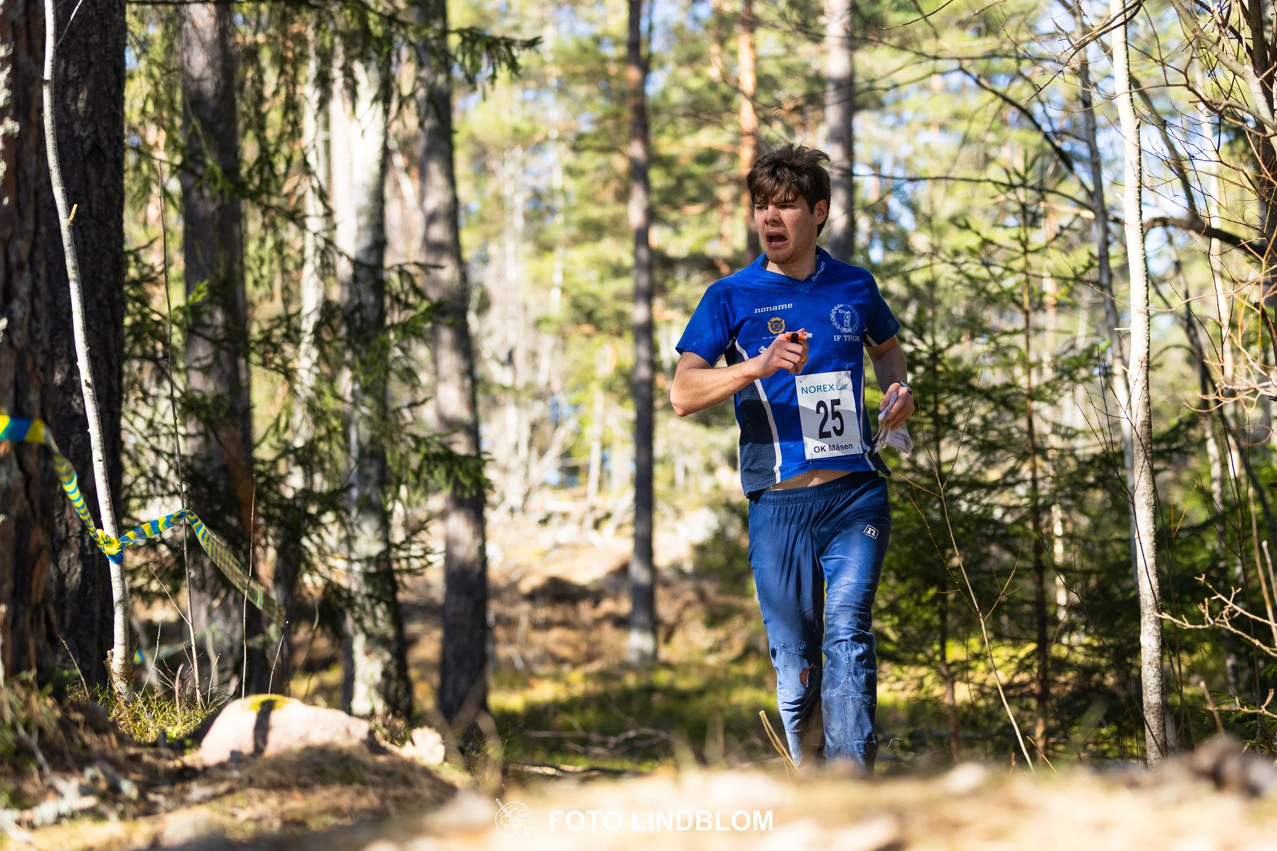 Swedish orienteering relay event Måsenstafetten 2026, with teams racing through forest terrain, captured by Foto Lindblom.