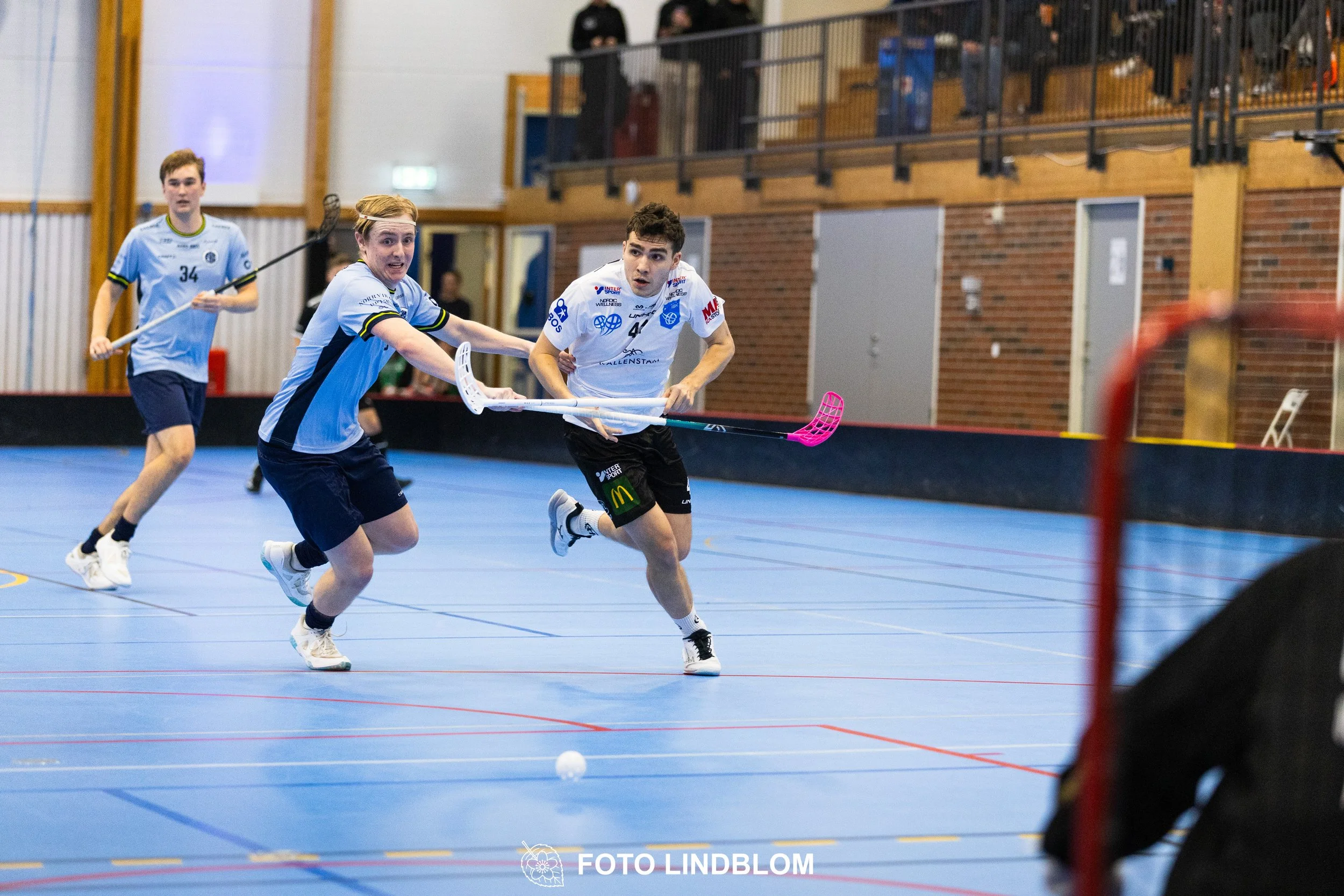 A picture of men playing floorball in Nacka IBK and FBC Sollentuna team gear