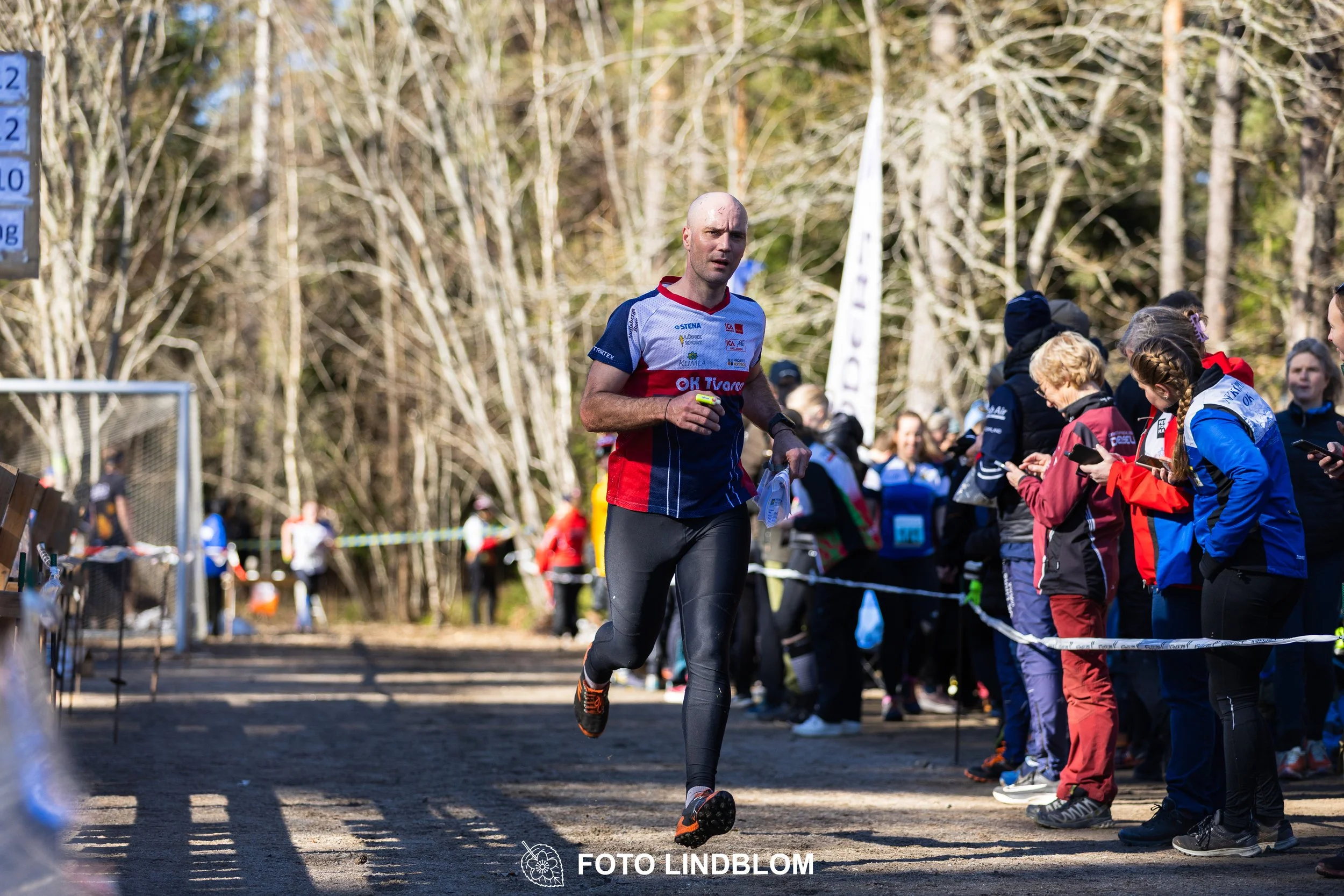 Swedish orienteering relay event Måsenstafetten 2026, with teams racing through forest terrain, captured by Foto Lindblom.