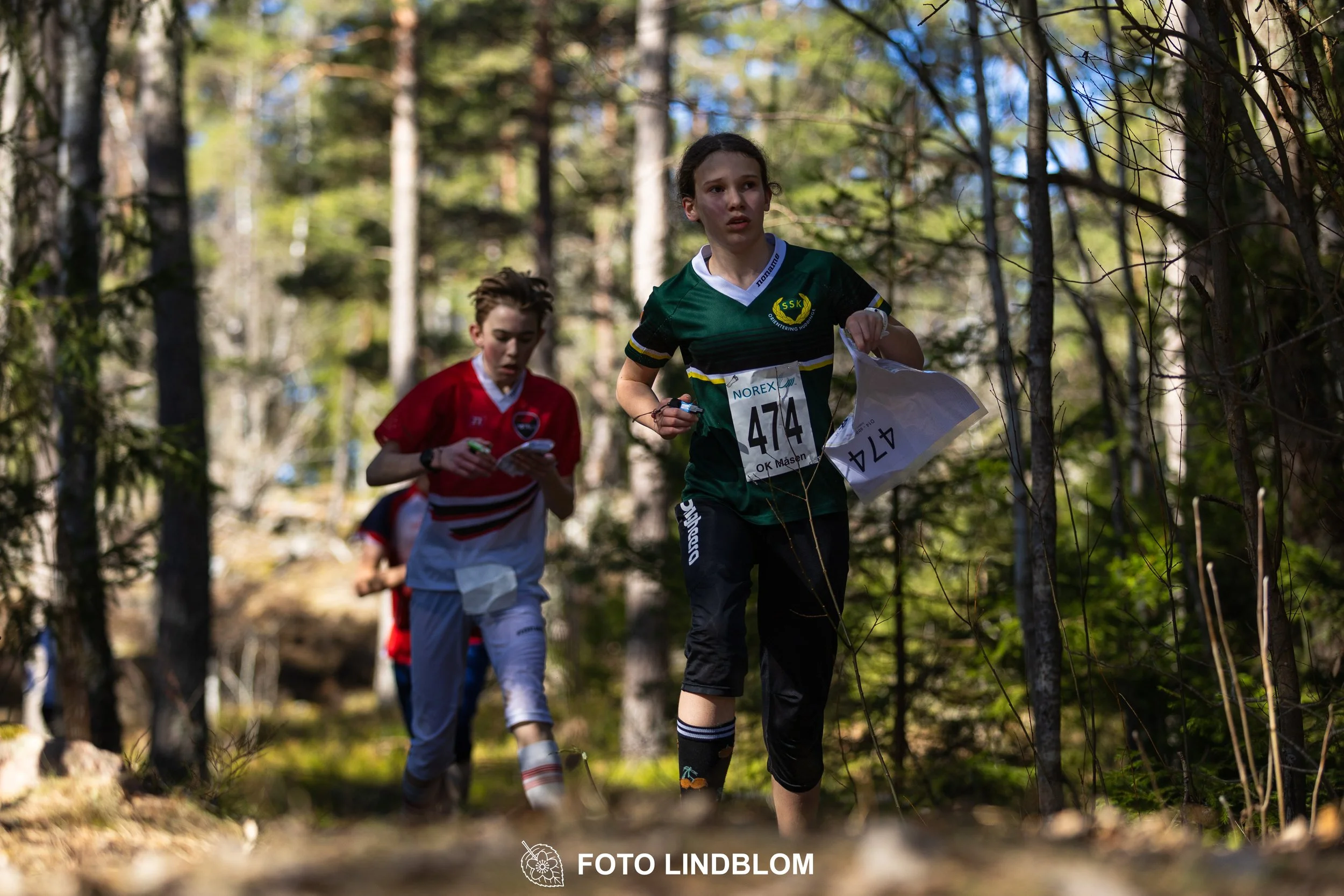 Forest relay orienteering at Måsenstafetten 2026, with teams competing in an endurance event, documented by Foto Lindblom.