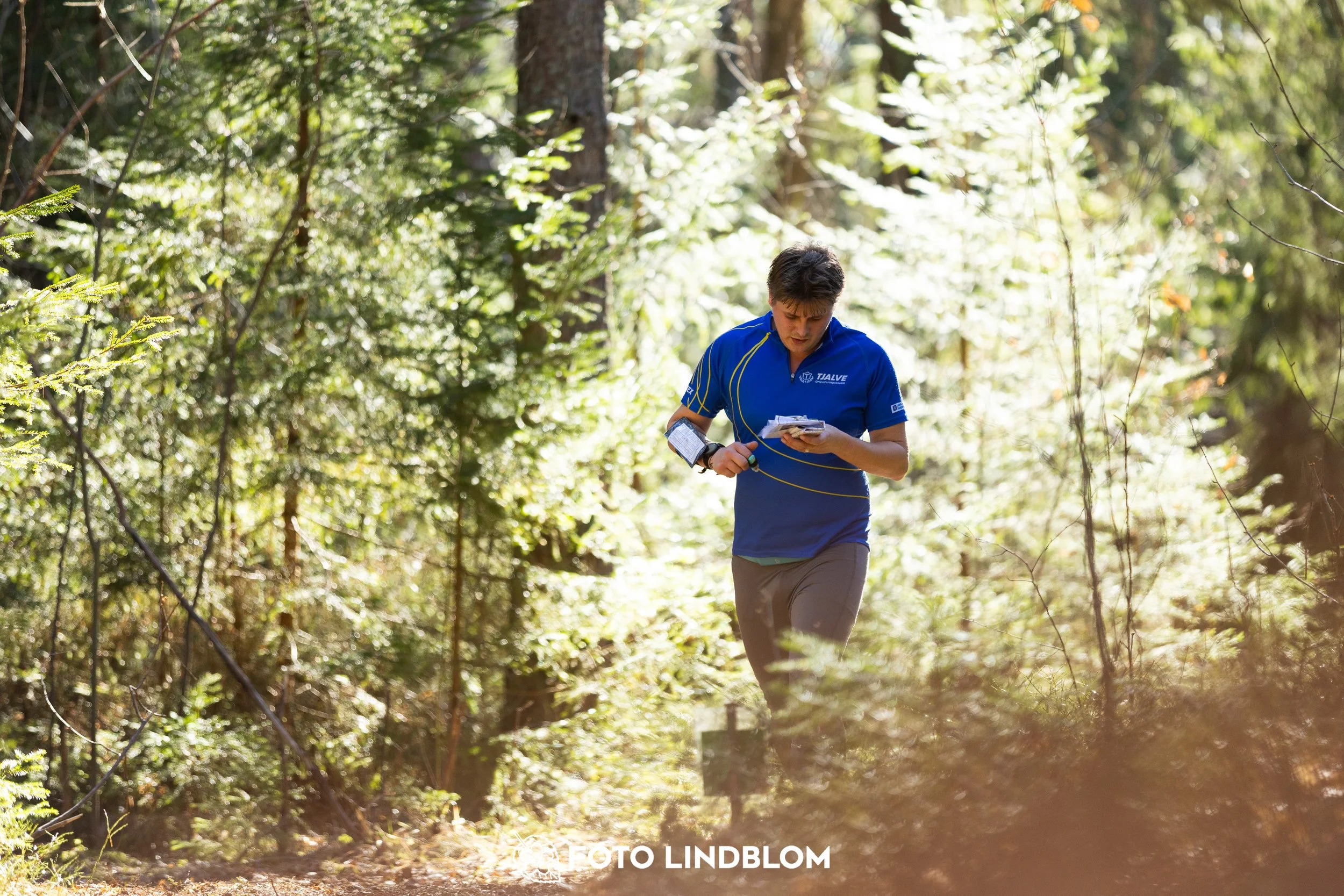 Image from Nyköpingsorienteringen 2026 showing competitors navigating forest terrain, taken by Foto Lindblom.