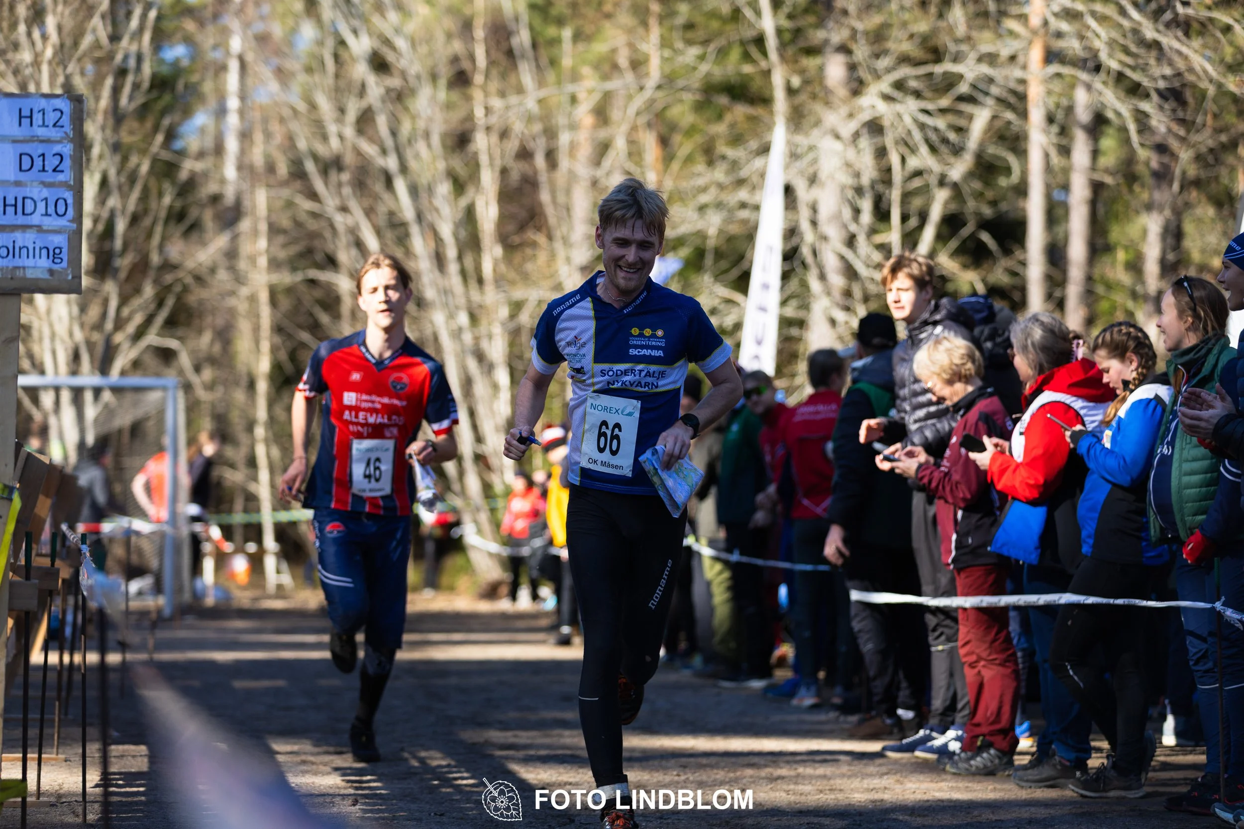 Forest relay orienteering at Måsenstafetten 2026, with teams competing in an endurance event, documented by Foto Lindblom.