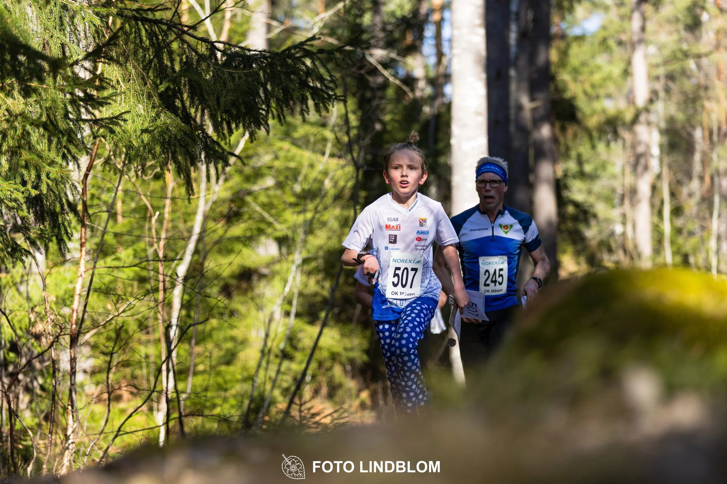 A relay-stage photo from Måsenstafetten 2026, featuring team-based orienteering competition, taken by Foto Lindblom.