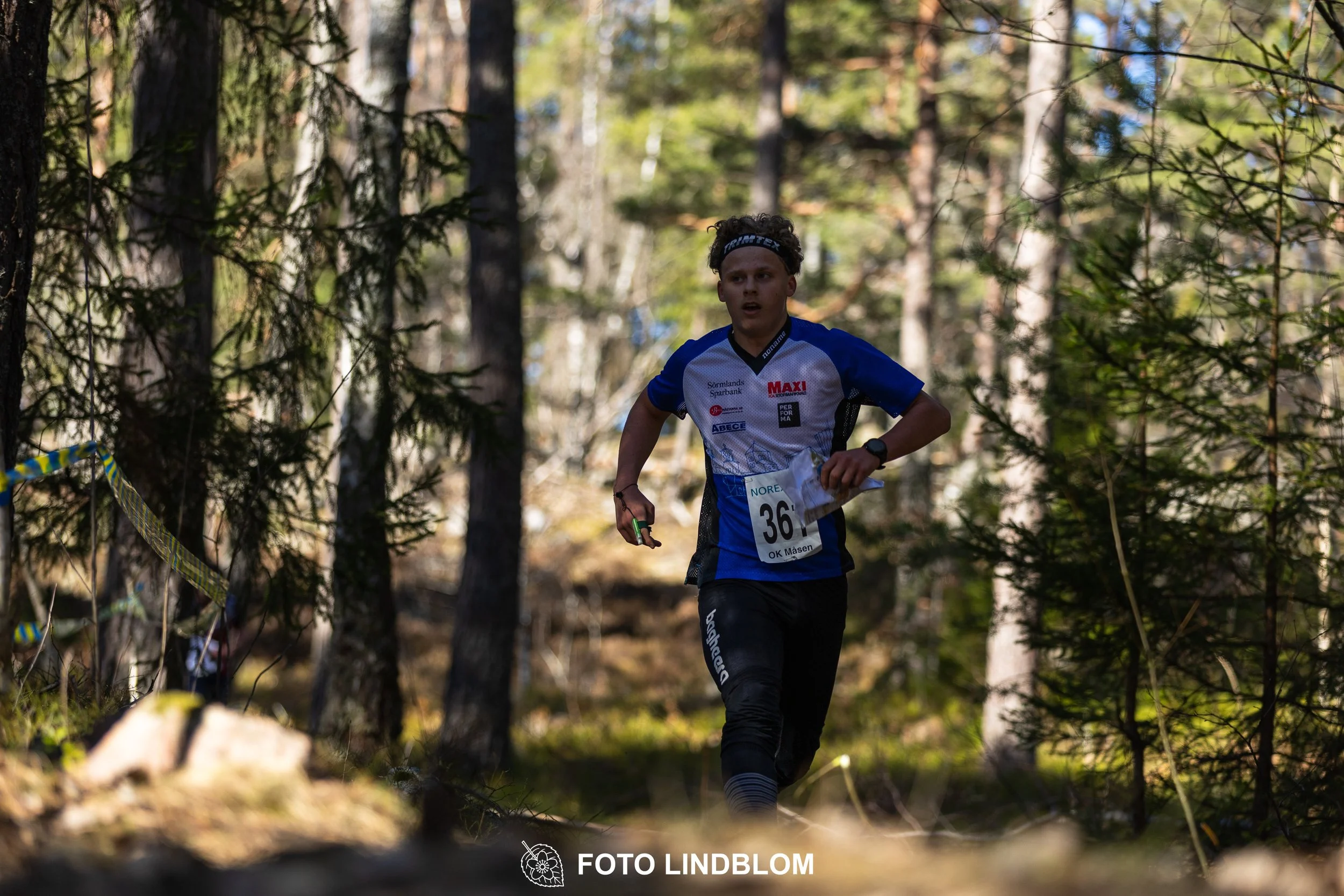 Swedish orienteering relay event Måsenstafetten 2026, with teams racing through forest terrain, captured by Foto Lindblom.
