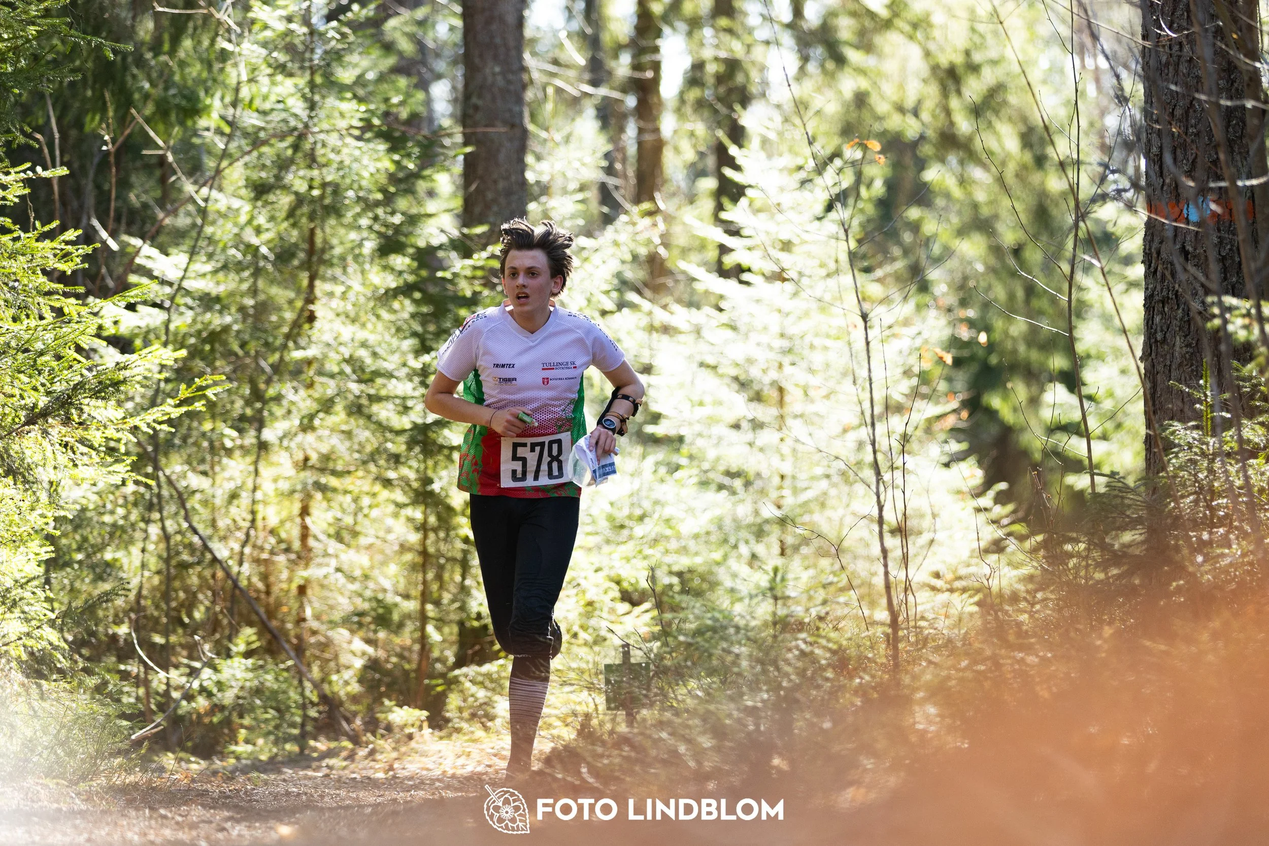 Image from Nyköpingsorienteringen 2026 showing competitors navigating forest terrain, taken by Foto Lindblom.