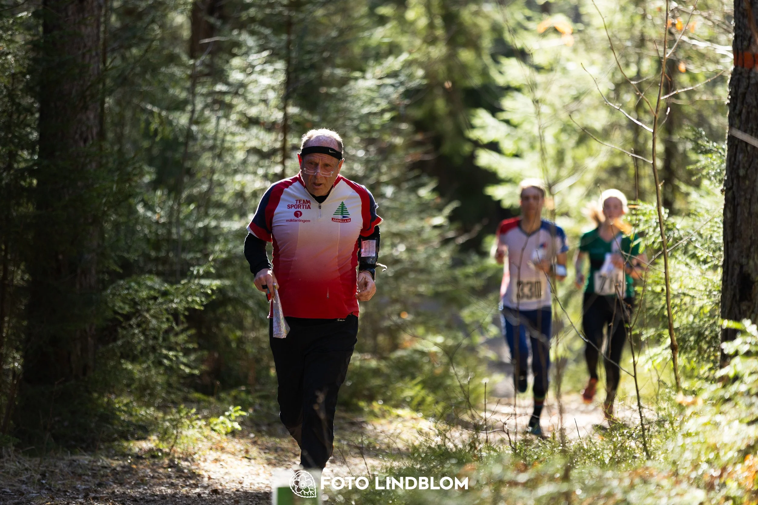 A photo from the 2026 Nyköpingsorienteringen orienteering event in a Swedish forest, captured by Foto Lindblom.