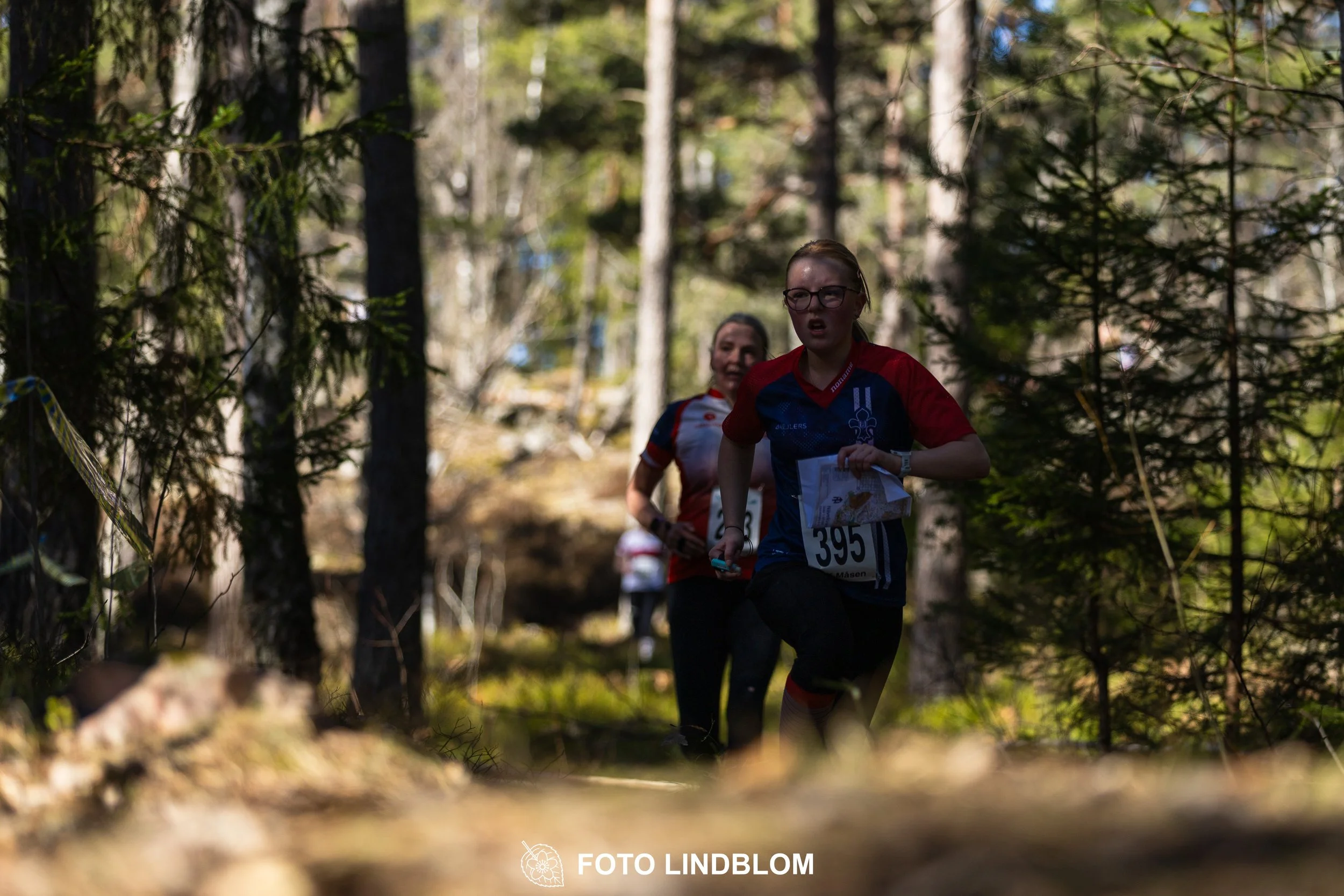 Swedish orienteering relay event Måsenstafetten 2026, with teams racing through forest terrain, captured by Foto Lindblom.
