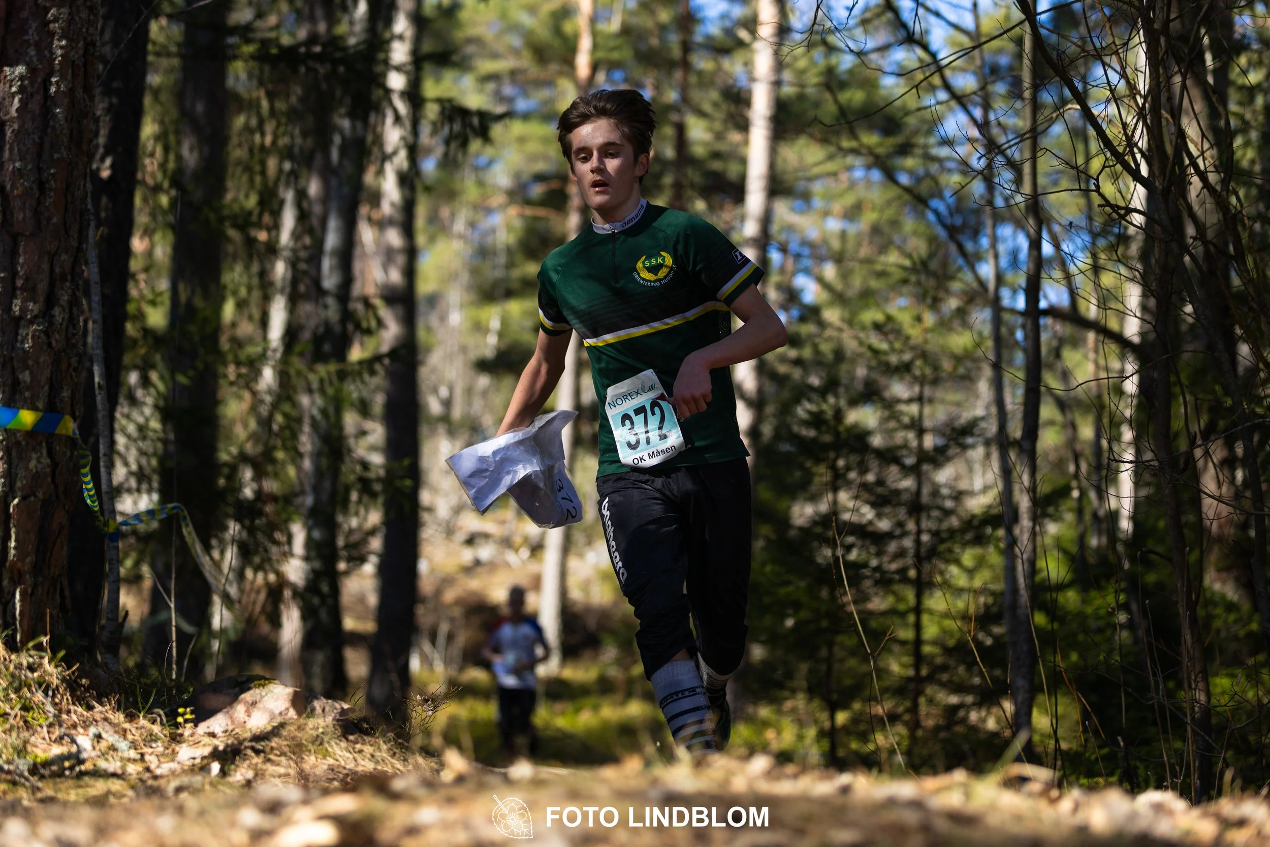Swedish orienteering relay event Måsenstafetten 2026, with teams racing through forest terrain, captured by Foto Lindblom.