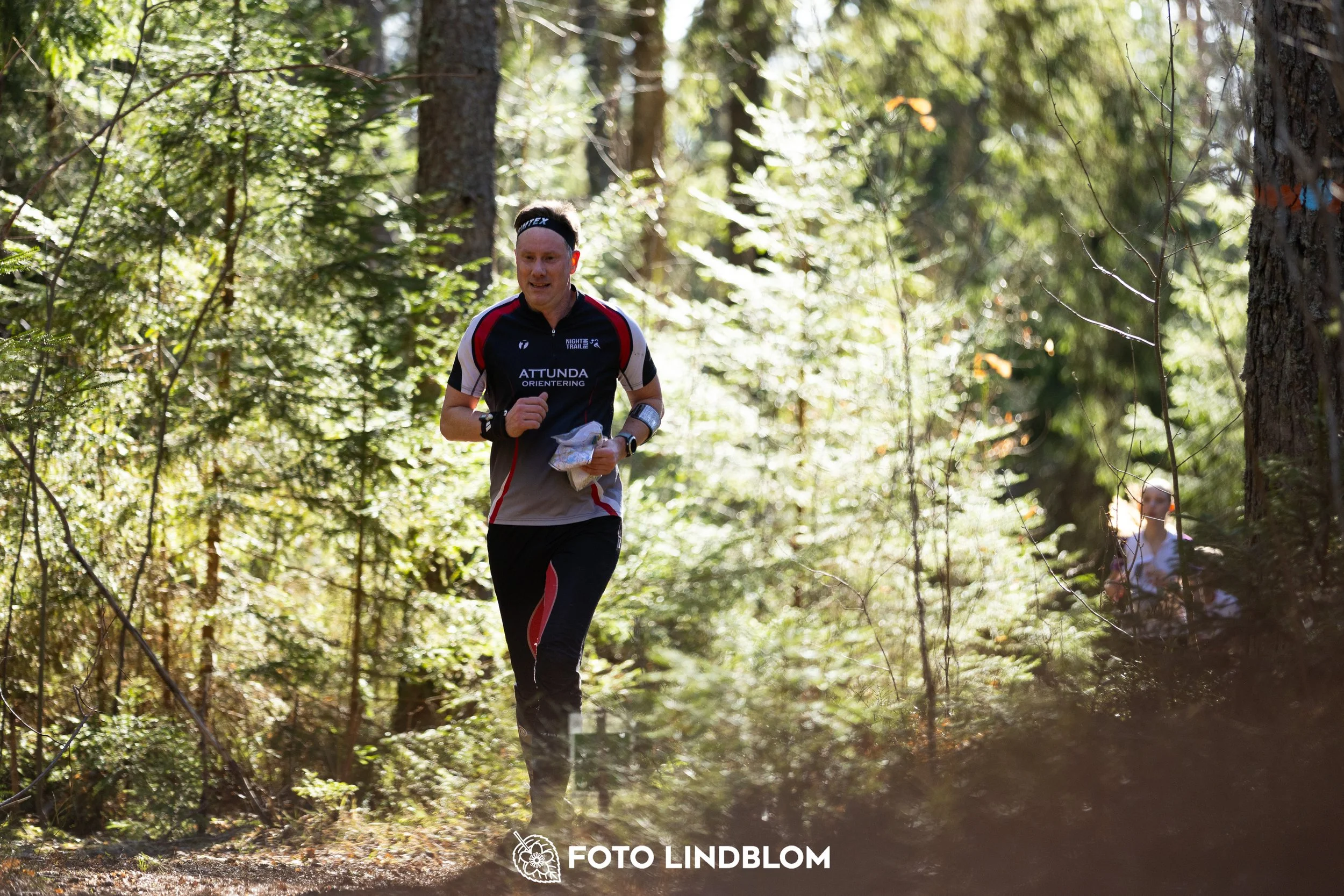 Image from Nyköpingsorienteringen 2026 showing competitors navigating forest terrain, taken by Foto Lindblom.