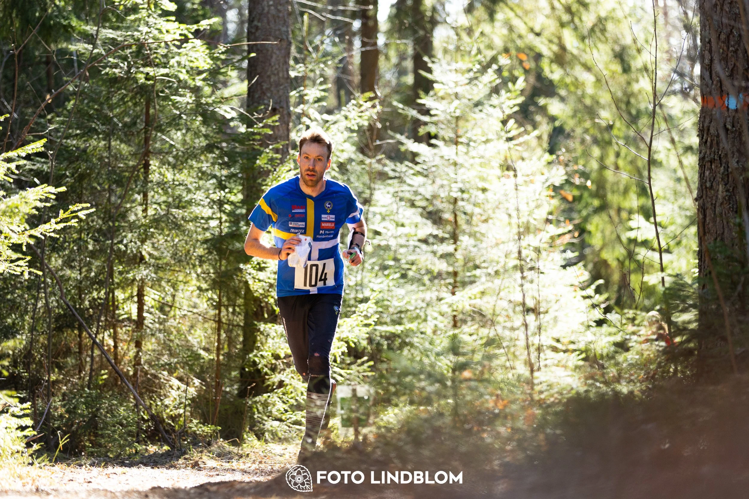 A photo from the 2026 Nyköpingsorienteringen orienteering event in a Swedish forest, captured by Foto Lindblom.