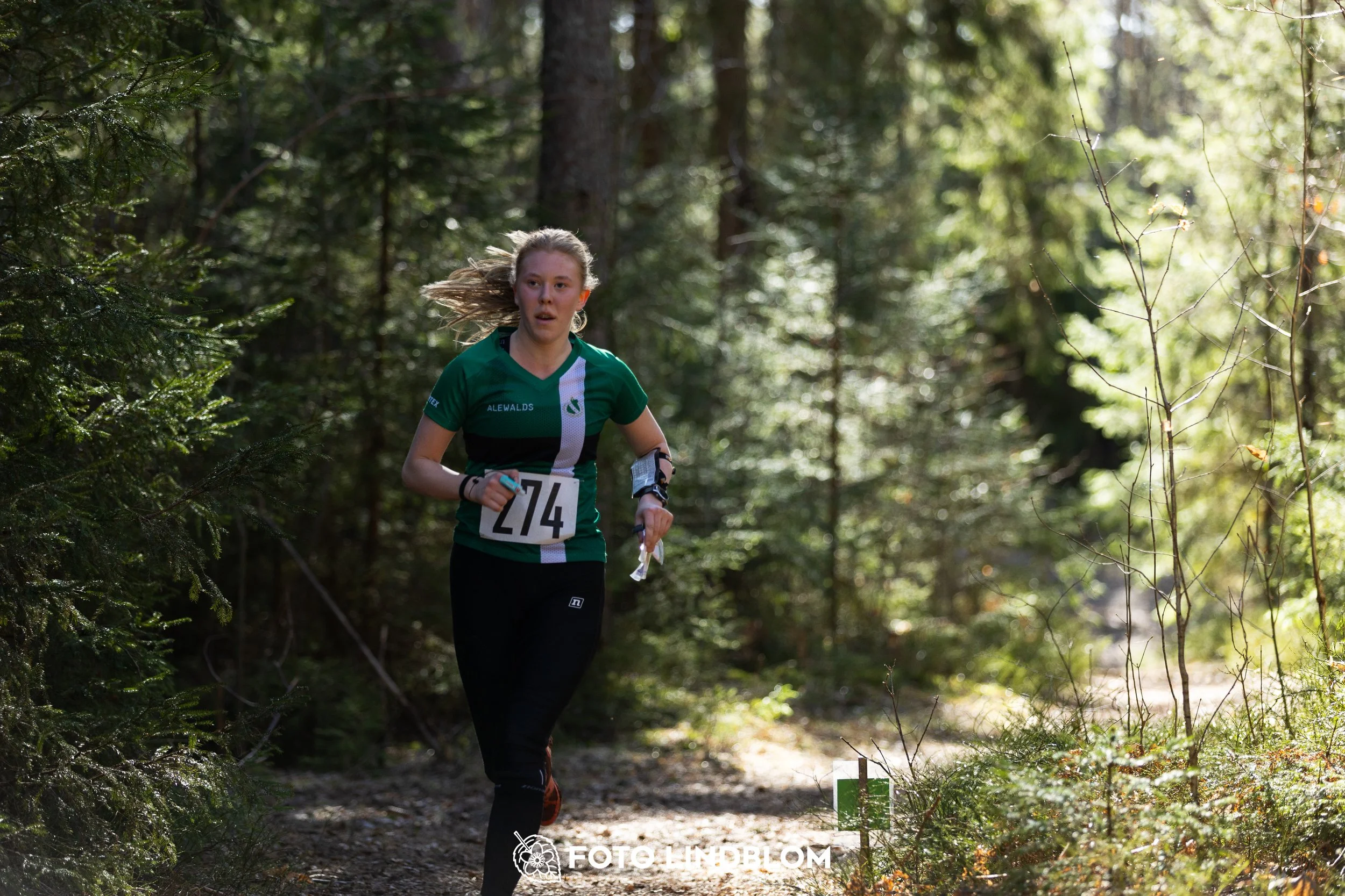 Image from Nyköpingsorienteringen 2026 showing competitors navigating forest terrain, taken by Foto Lindblom.