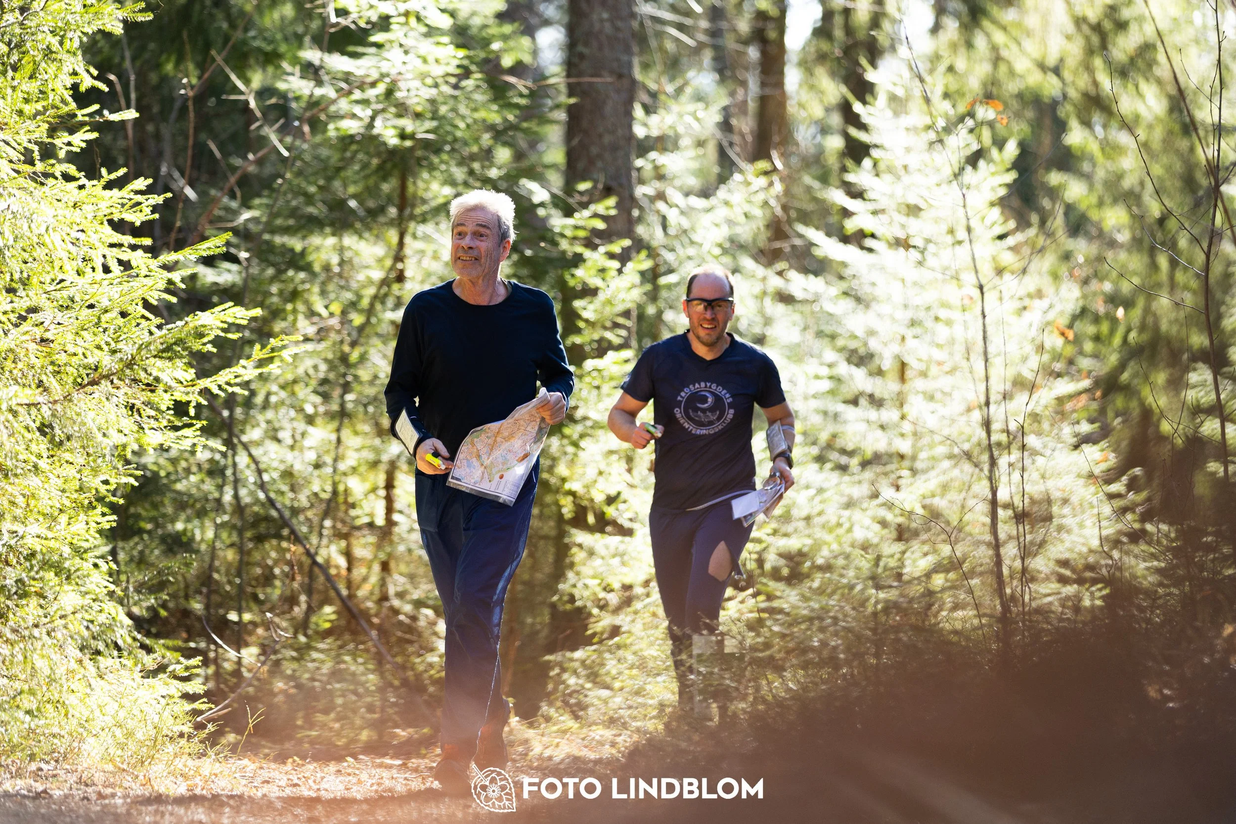 Image from Nyköpingsorienteringen 2026 showing competitors navigating forest terrain, taken by Foto Lindblom.