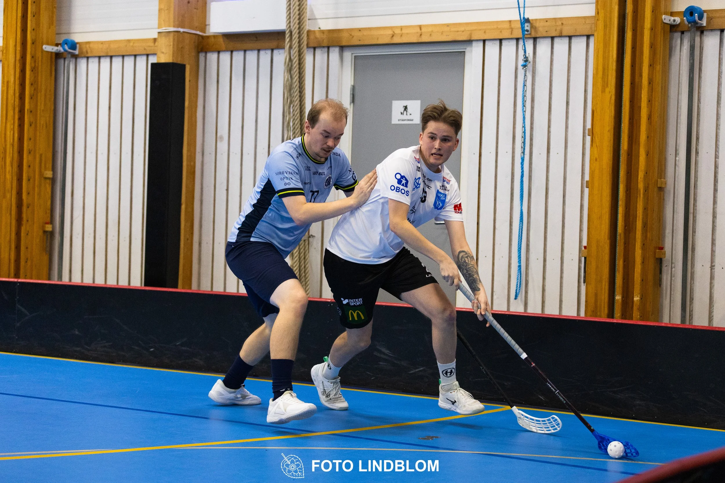 A picture of men playing floorball in Nacka IBK and FBC Sollentuna team gear