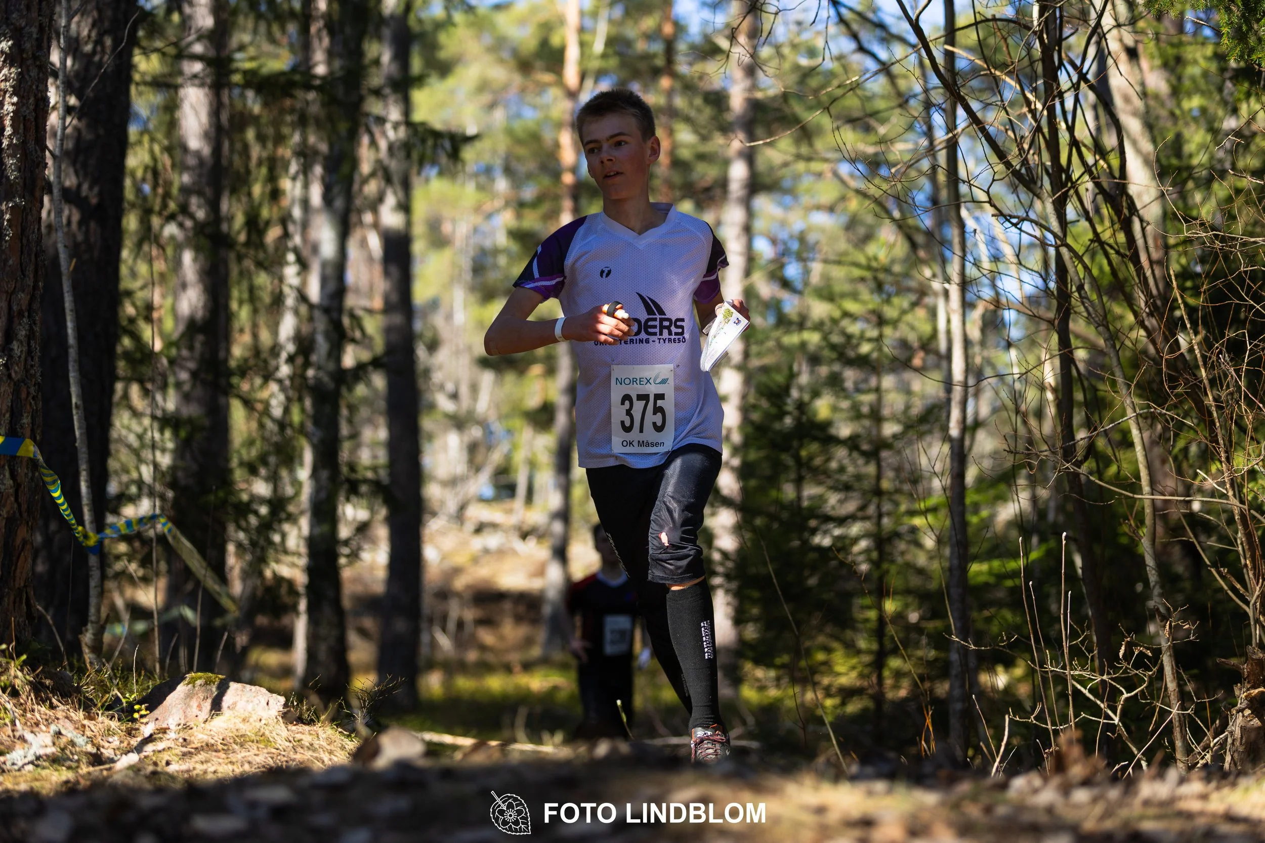Swedish orienteering relay event Måsenstafetten 2026, with teams racing through forest terrain, captured by Foto Lindblom.