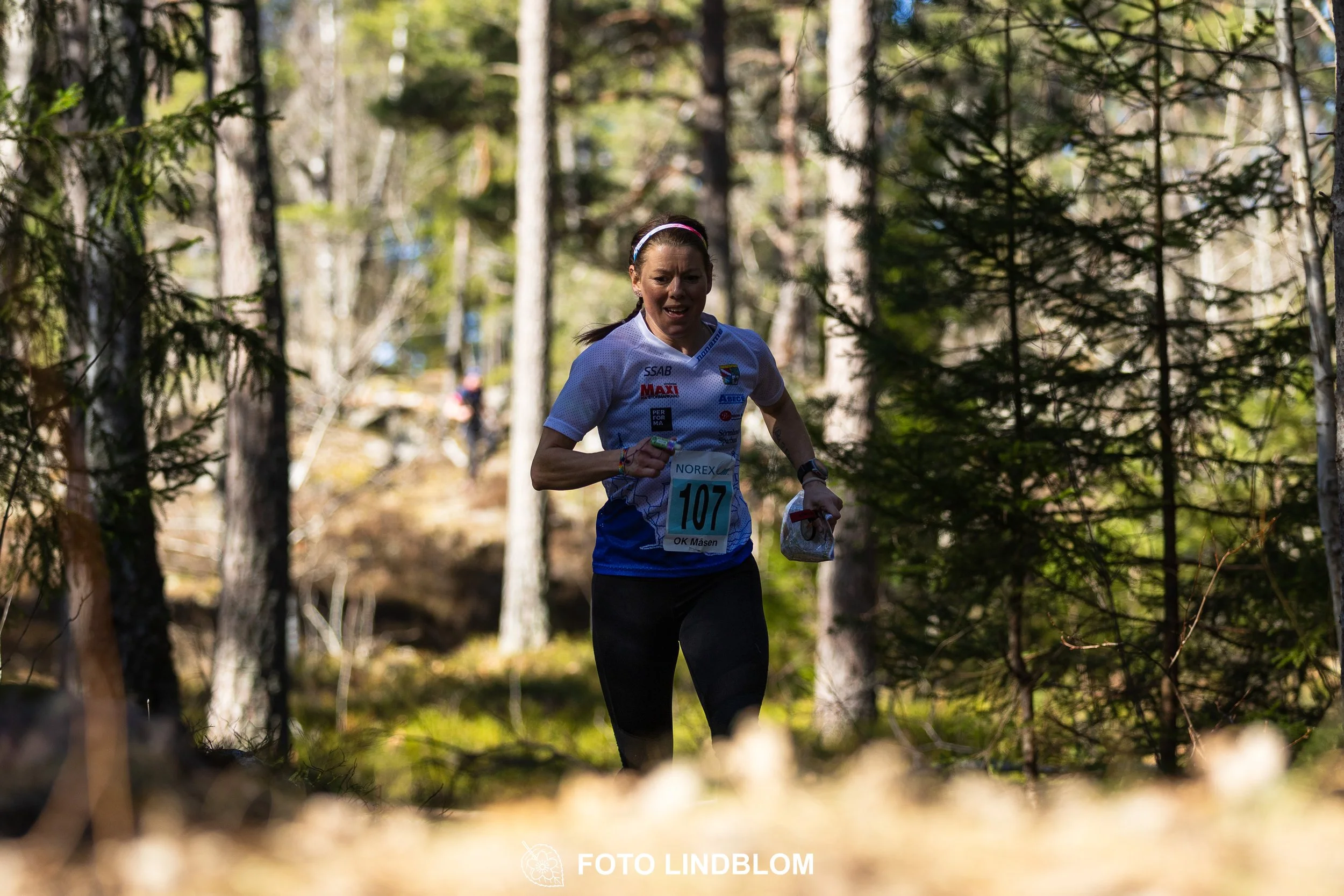 Swedish orienteering relay event Måsenstafetten 2026, with teams racing through forest terrain, captured by Foto Lindblom.