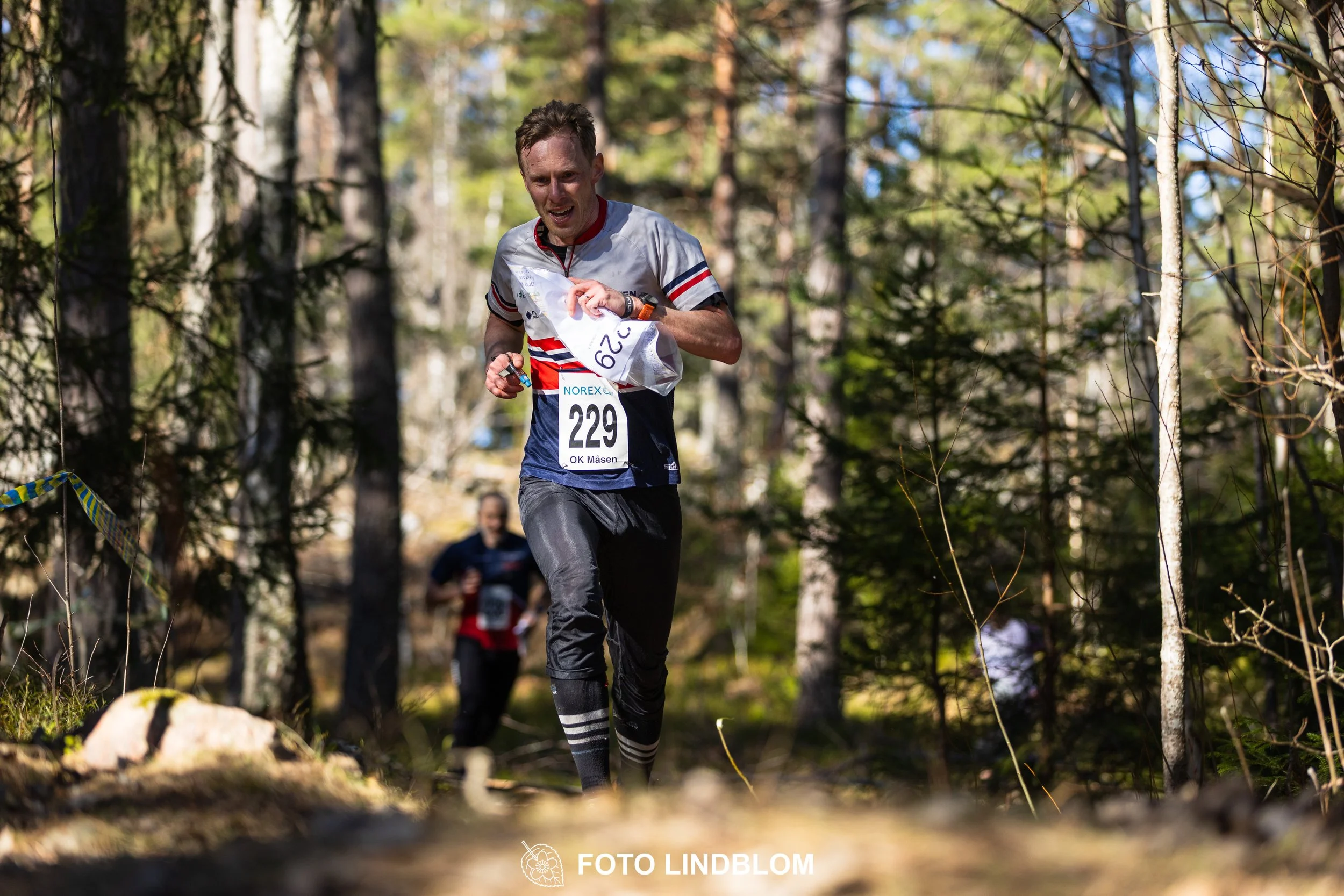 Swedish orienteering relay event Måsenstafetten 2026, with teams racing through forest terrain, captured by Foto Lindblom.