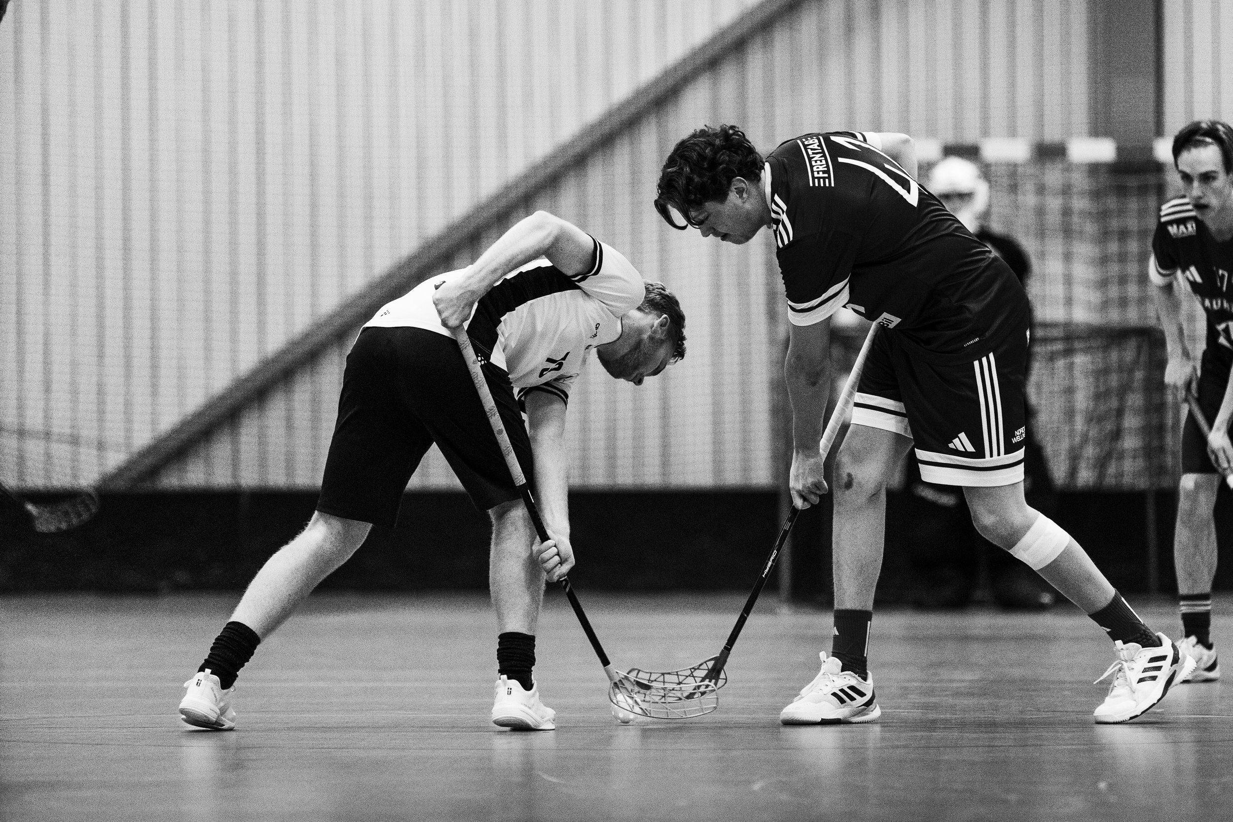 Two male floorball players in a face-off.