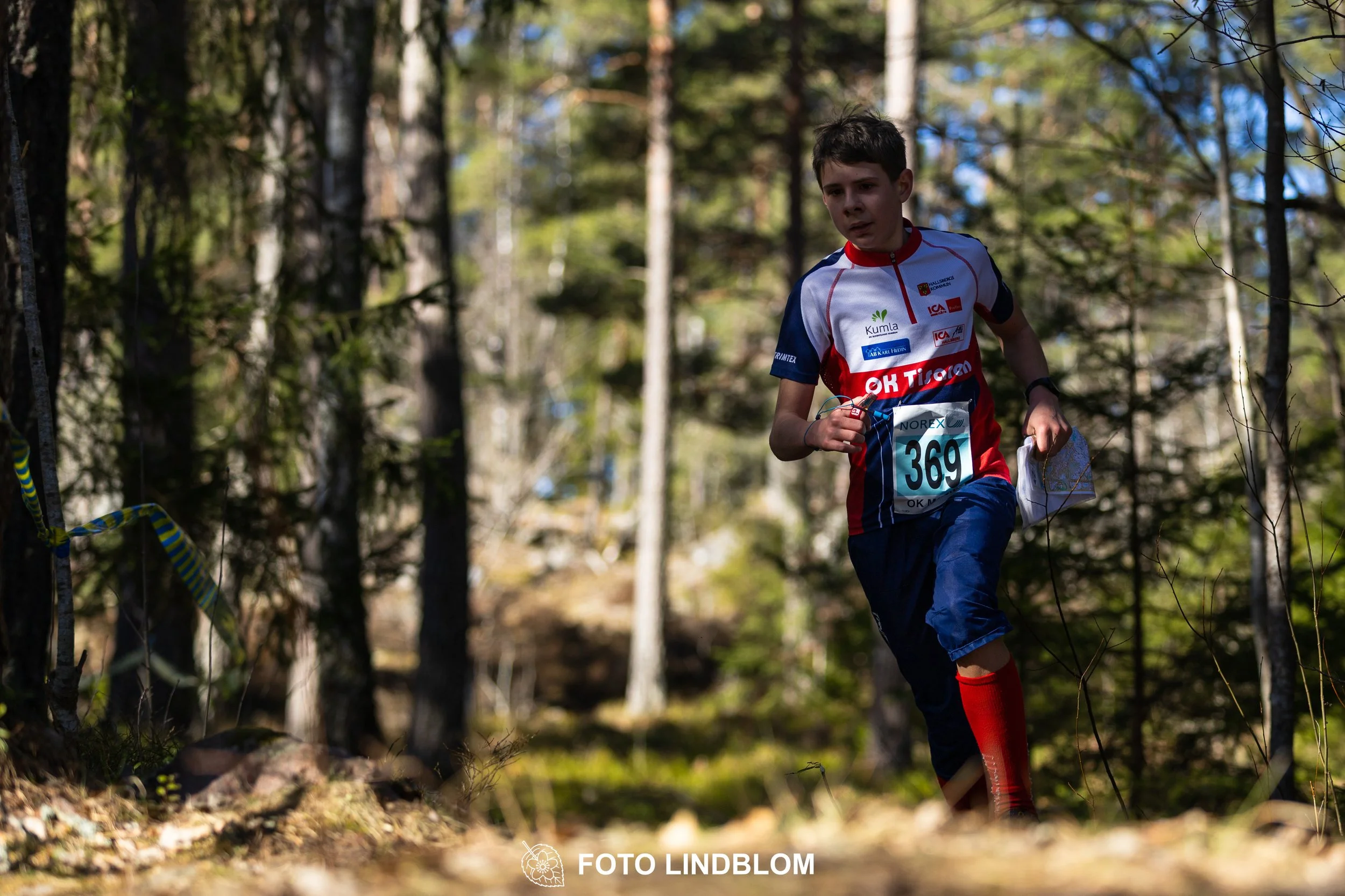 Swedish orienteering relay event Måsenstafetten 2026, with teams racing through forest terrain, captured by Foto Lindblom.