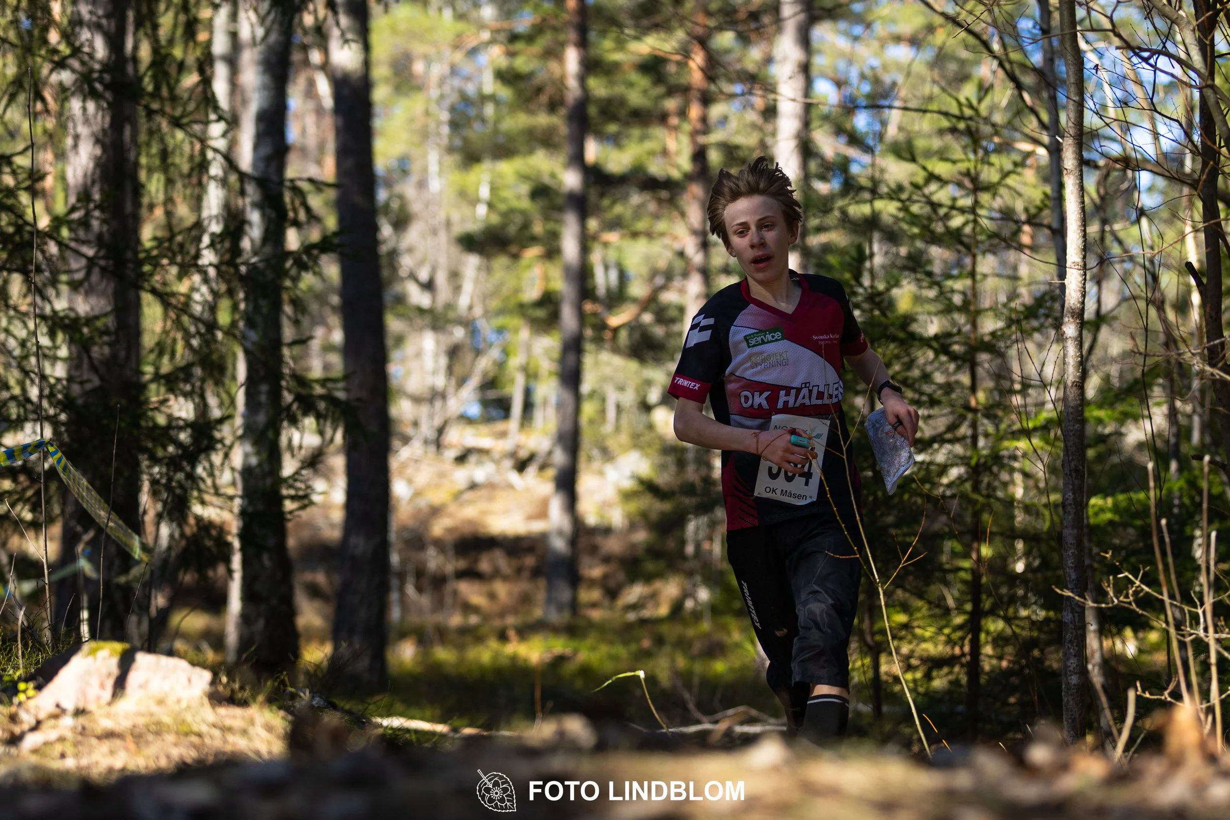 Swedish orienteering relay event Måsenstafetten 2026, with teams racing through forest terrain, captured by Foto Lindblom.