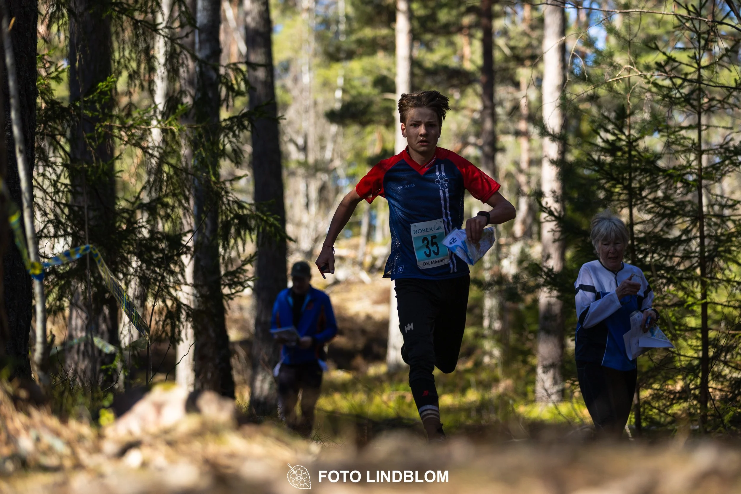 Team relay action at Måsenstafetten 2026, an orienteering competition in forest terrain, photographed by Foto Lindblom.