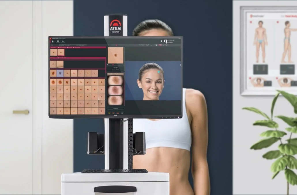A woman at a dermatology or skincare clinic undergoing skin analysis with a computer displaying her face and skin details.
