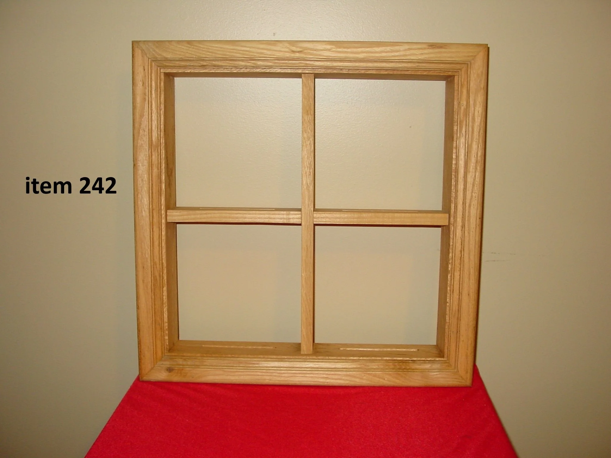 A wooden picture frame with four sections, labeled item 242, placed on a red surface against a light-colored wall.