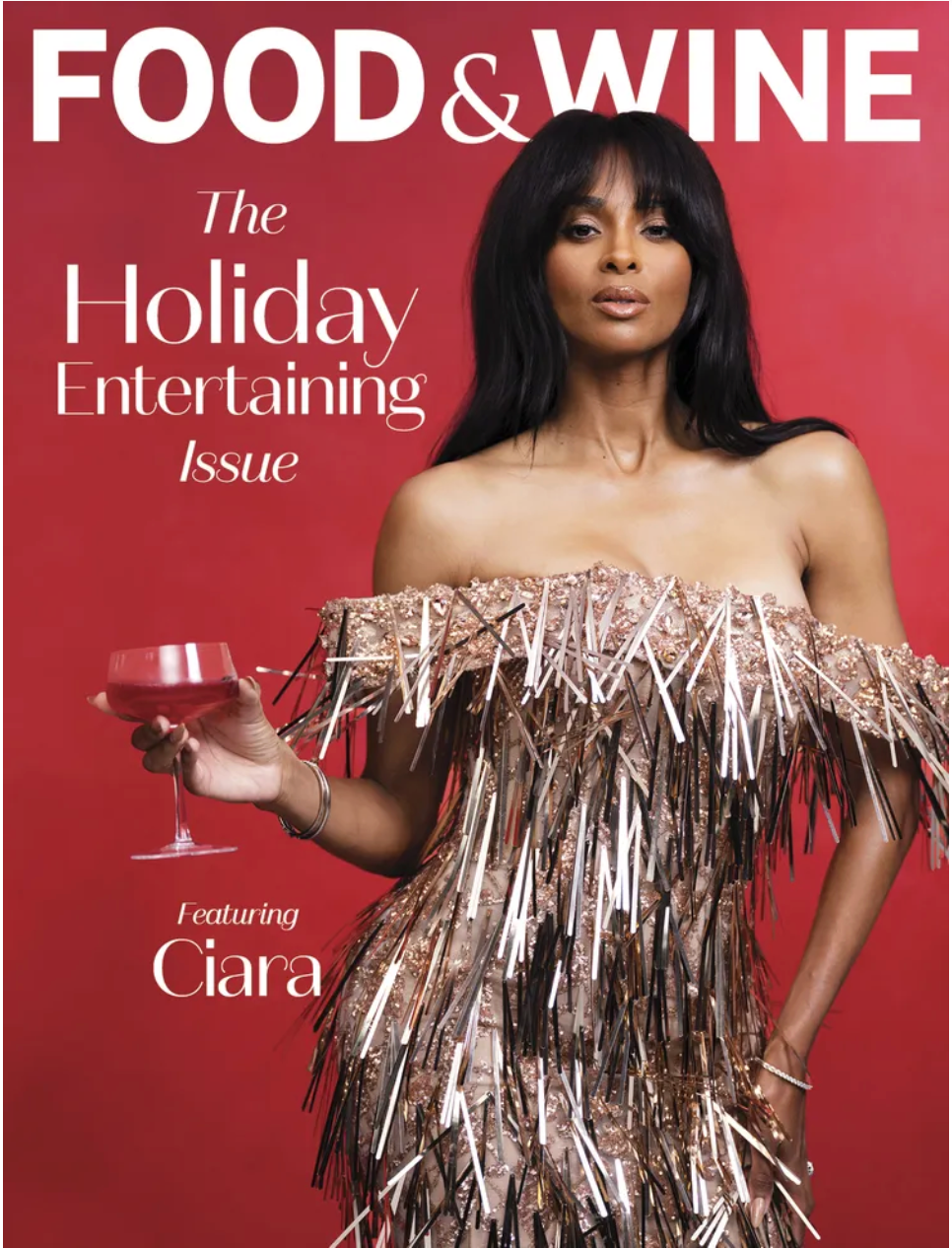Magazine cover titled "Food & Wine" featuring a woman in a strapless, metallic, feathered dress holding a glass of red wine against a red background, with the text "The Holiday Entertaining Issue" and "Featuring Ciara".
