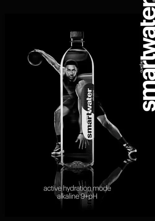 A fitness-themed advertisement featuring a water bottle with a man in a stretching pose inside it. The bottle has a label with the brand name "smart water". The background is black, with the product and man highlighted. Text at the bottom reads "acti