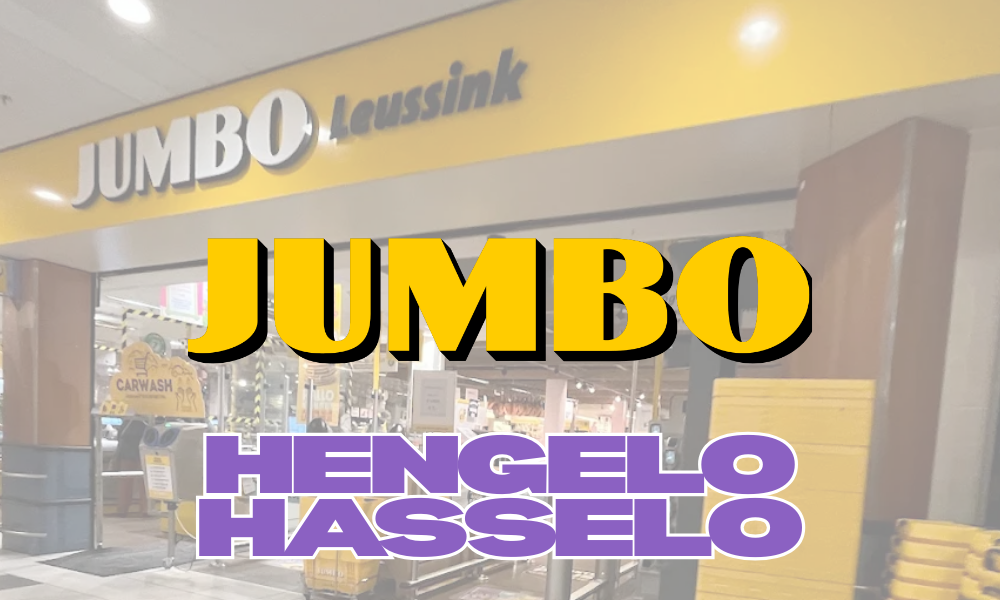 Ingang van een Jumbo supermarkt met grote, kleurrijke tekst die 'JUMBO HENGELO HASSELO' zegt, een Carwash plek is zichtbaar in de achtergrond.