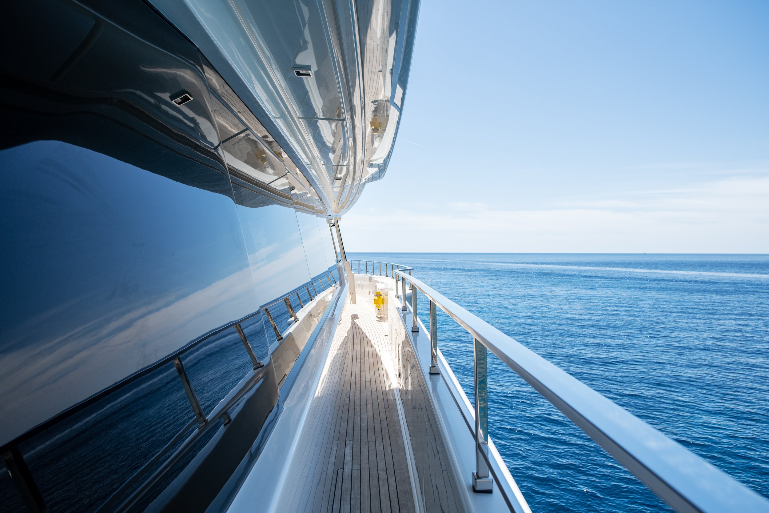 View from the deck of a yacht showing a calm blue ocean and clear sky.