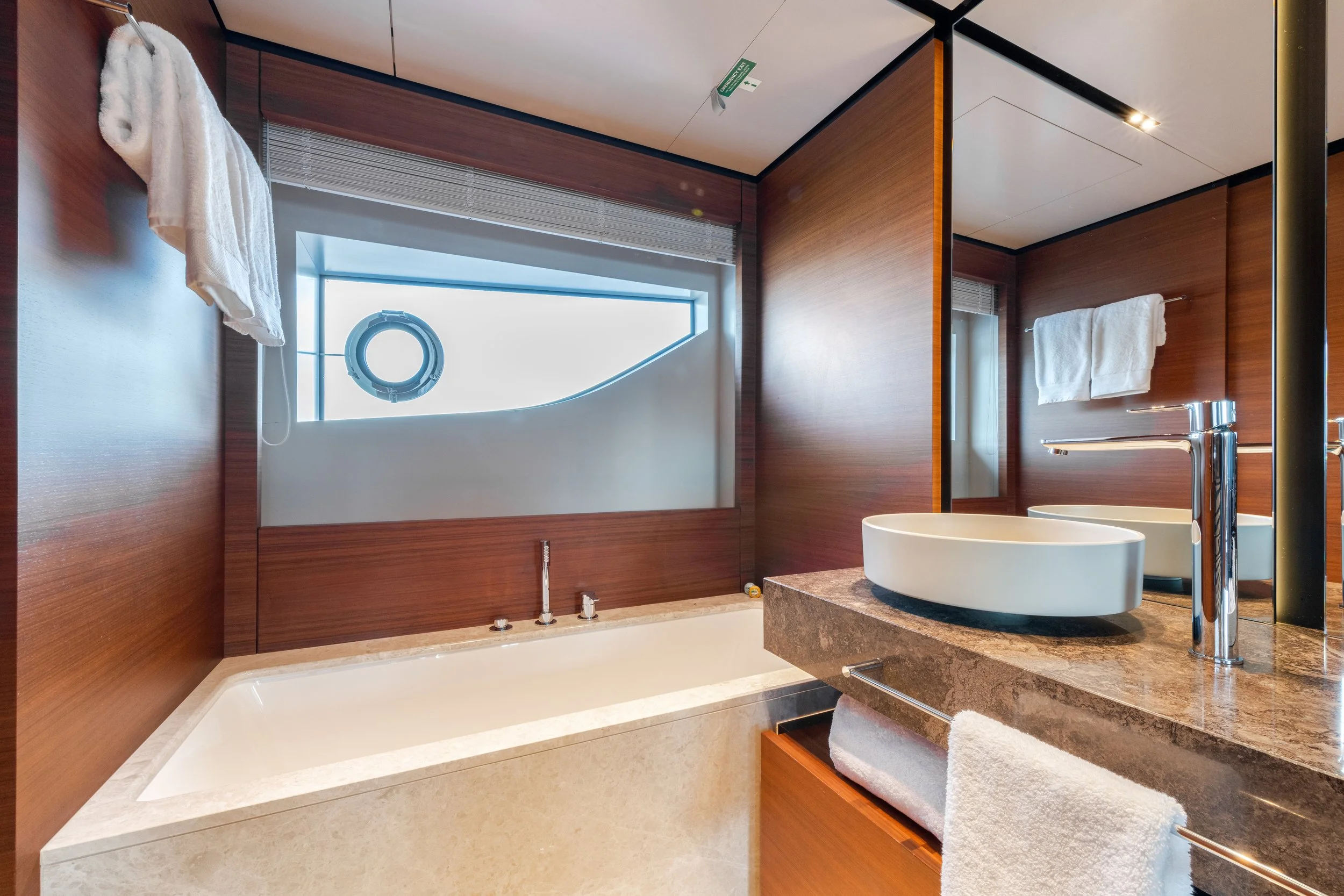 Modern bathroom with a beige bathtub, a large mirror, a white vessel sink, and wooden wall panels.