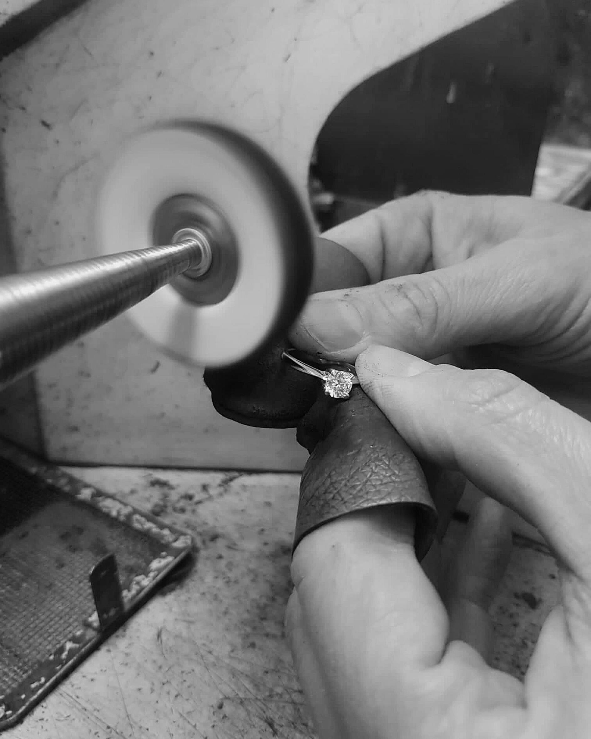 Un gioielliere lavora su un anello solitario in un laboratorio di oreficeria.