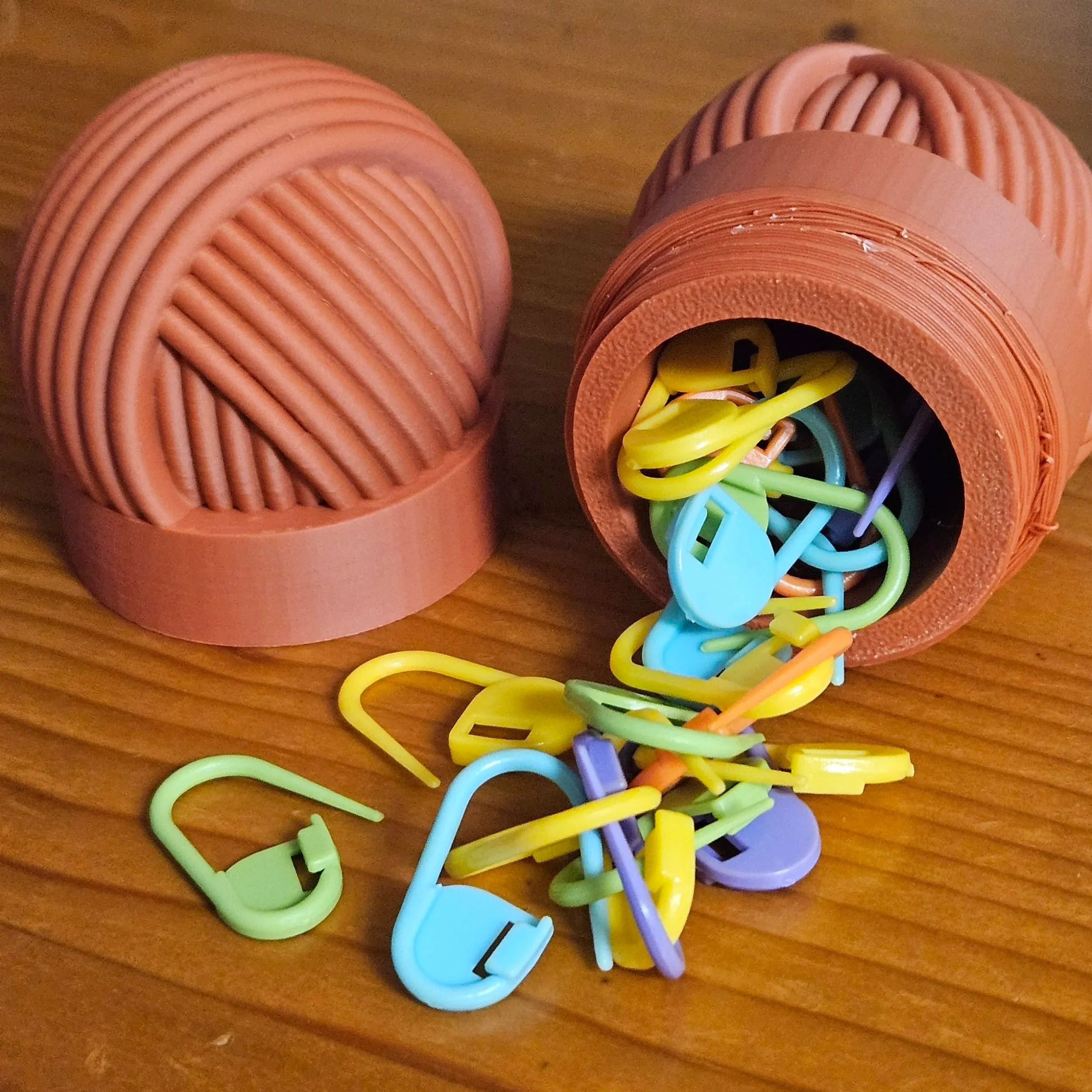 A plastic container with colorful plastic hooks spilling out onto a wooden surface.