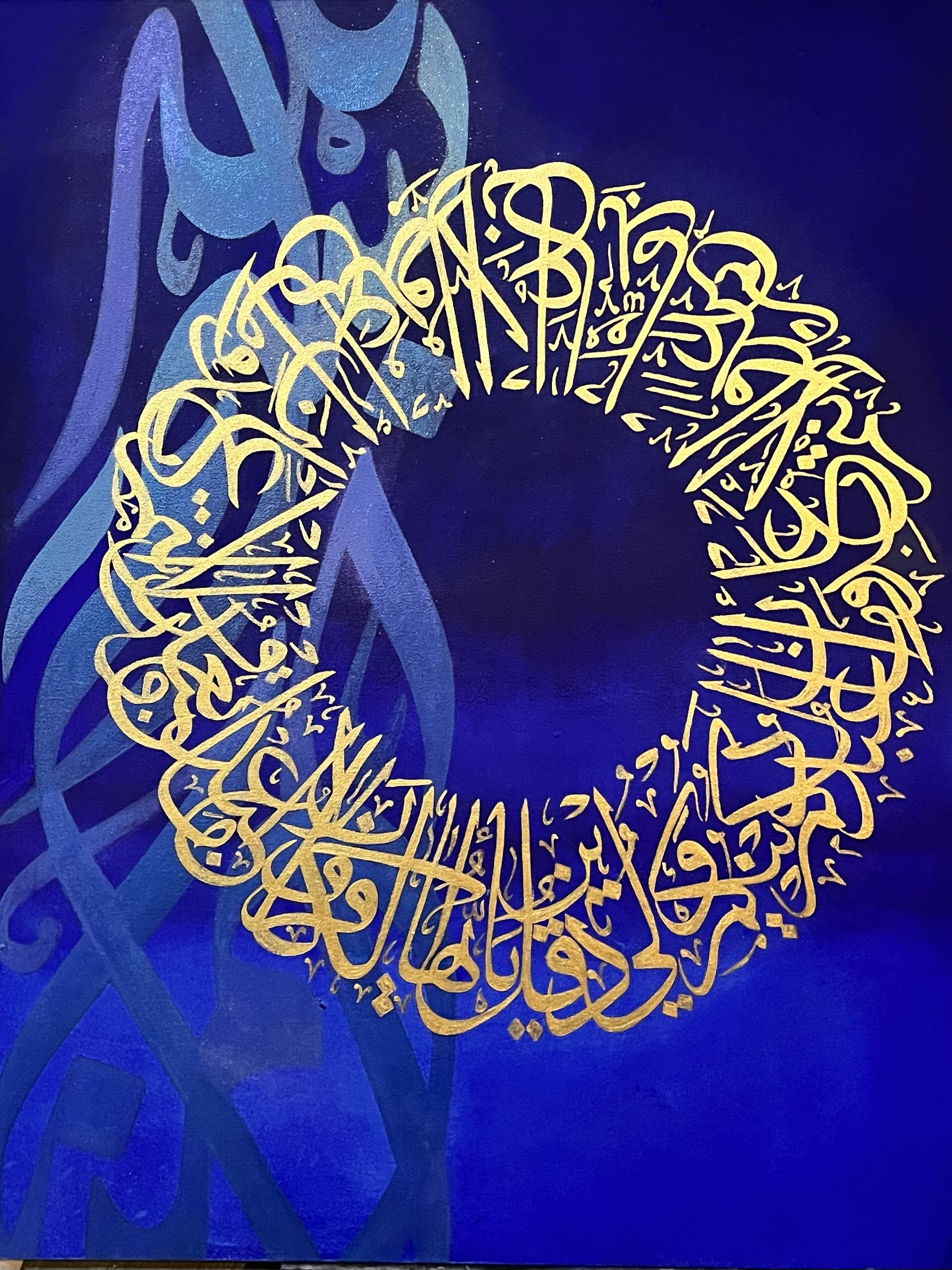 Gold Arabic calligraphy arranged in a circular pattern on a royal blue background with floral and abstract motifs.