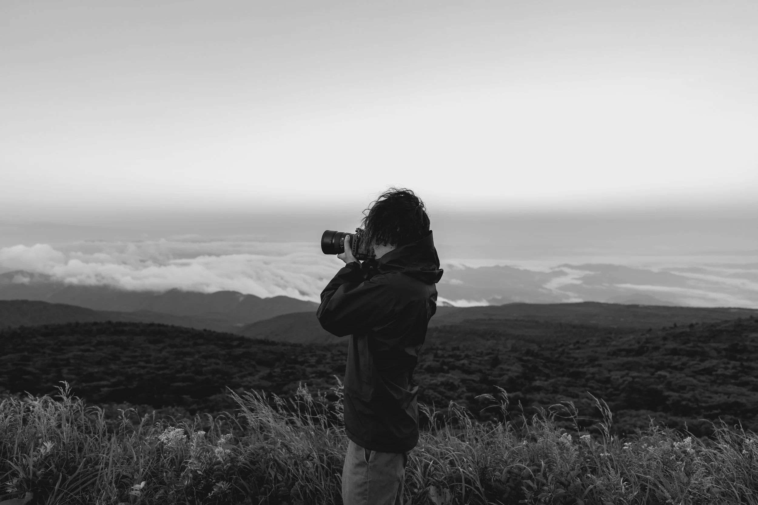 山間の景色を撮影する人の黒と白の写真