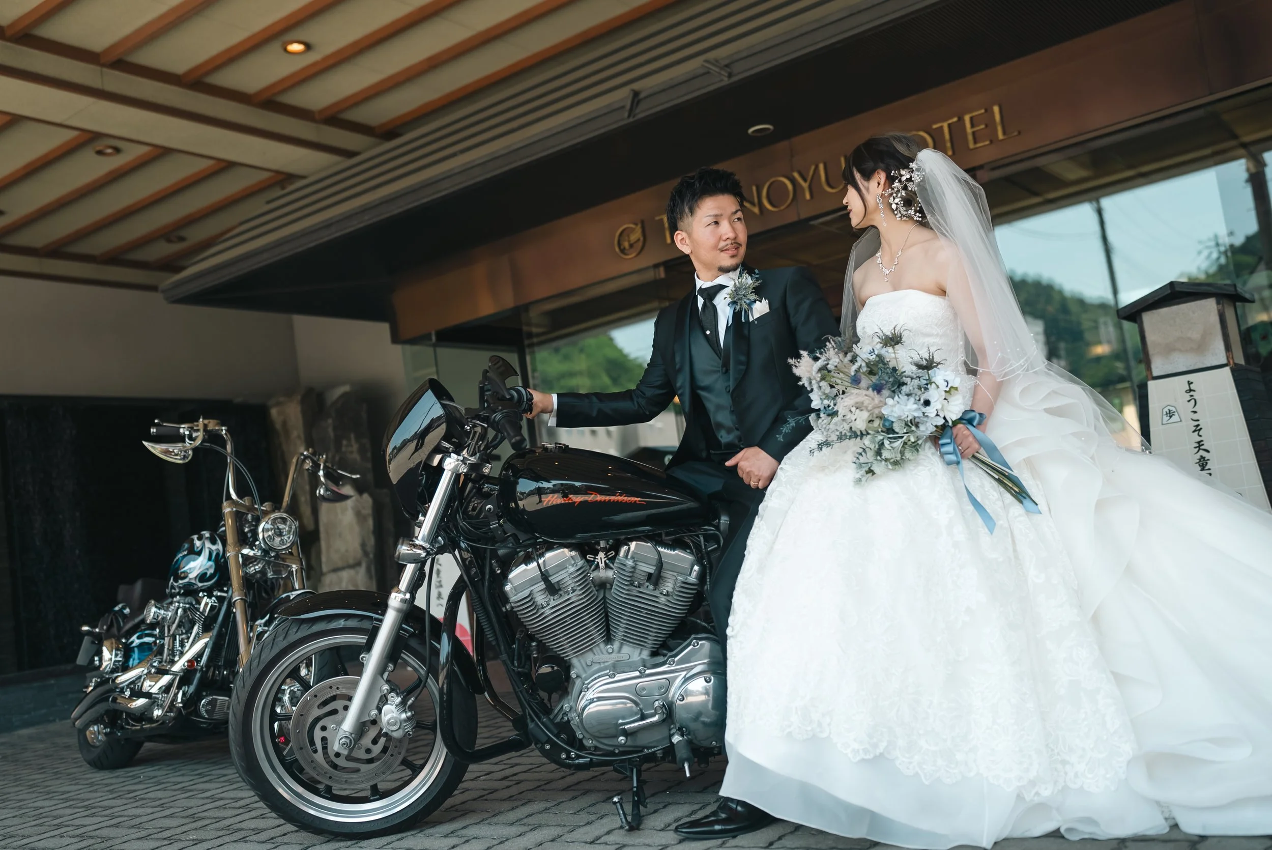バイクの前に立つ新郎とウェディングドレスの新婦。