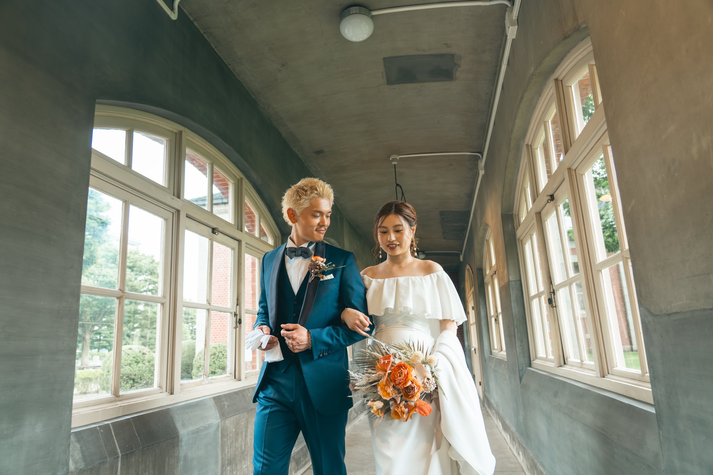 結婚式を挙げている新郎新婦が白い花嫁衣裳とブルースーツを着て、幸せそうに歩いている