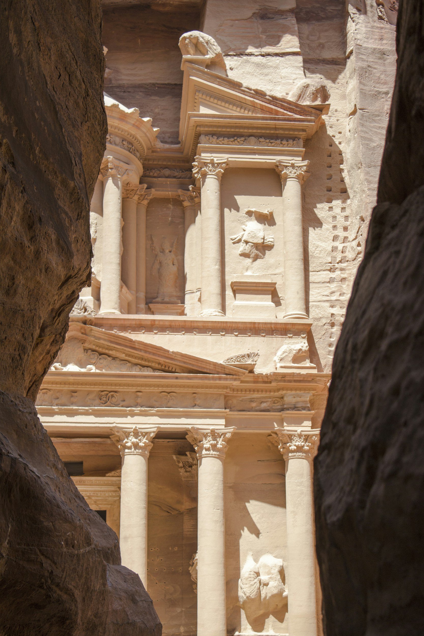 View of the ancient rock-cut city of Petra, Jordan, showing elaborate facades and columns carved into rose-colored rock.
