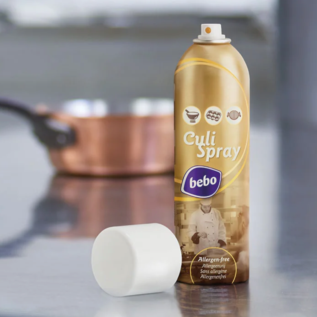 Een bus Culi Spray van Bebo met witte dop op een keukenwerkblad, met een pan op de achtergrond.