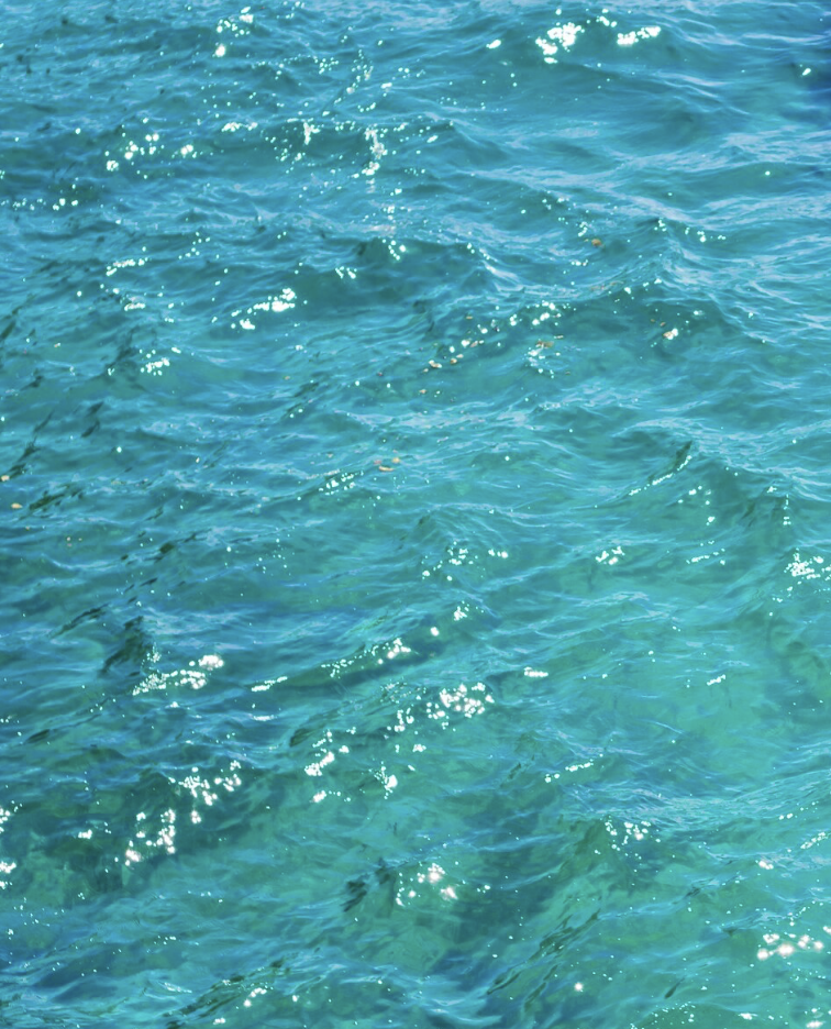 Clear turquoise ocean water with sunlight reflections on the surface.