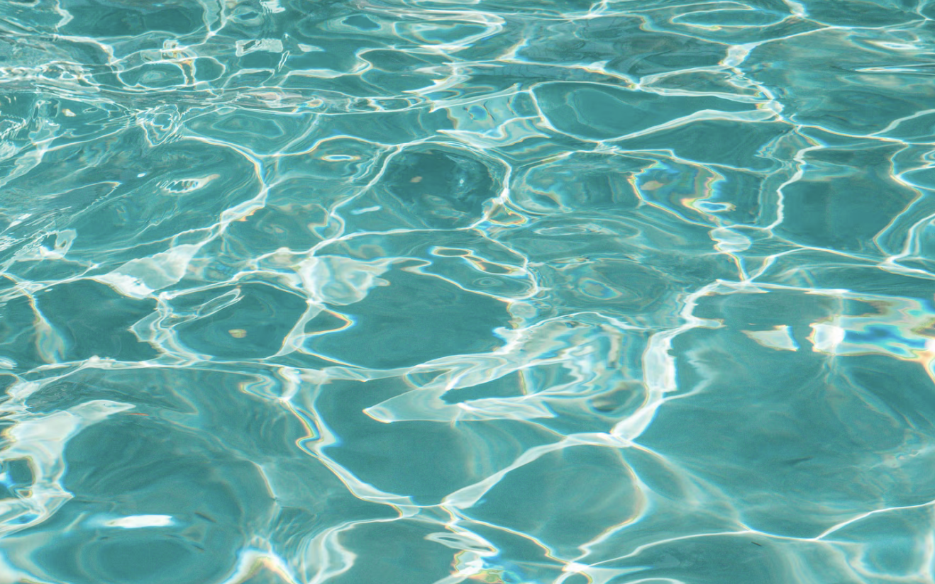 Photo of clear turquoise ocean water with sunlight reflections.