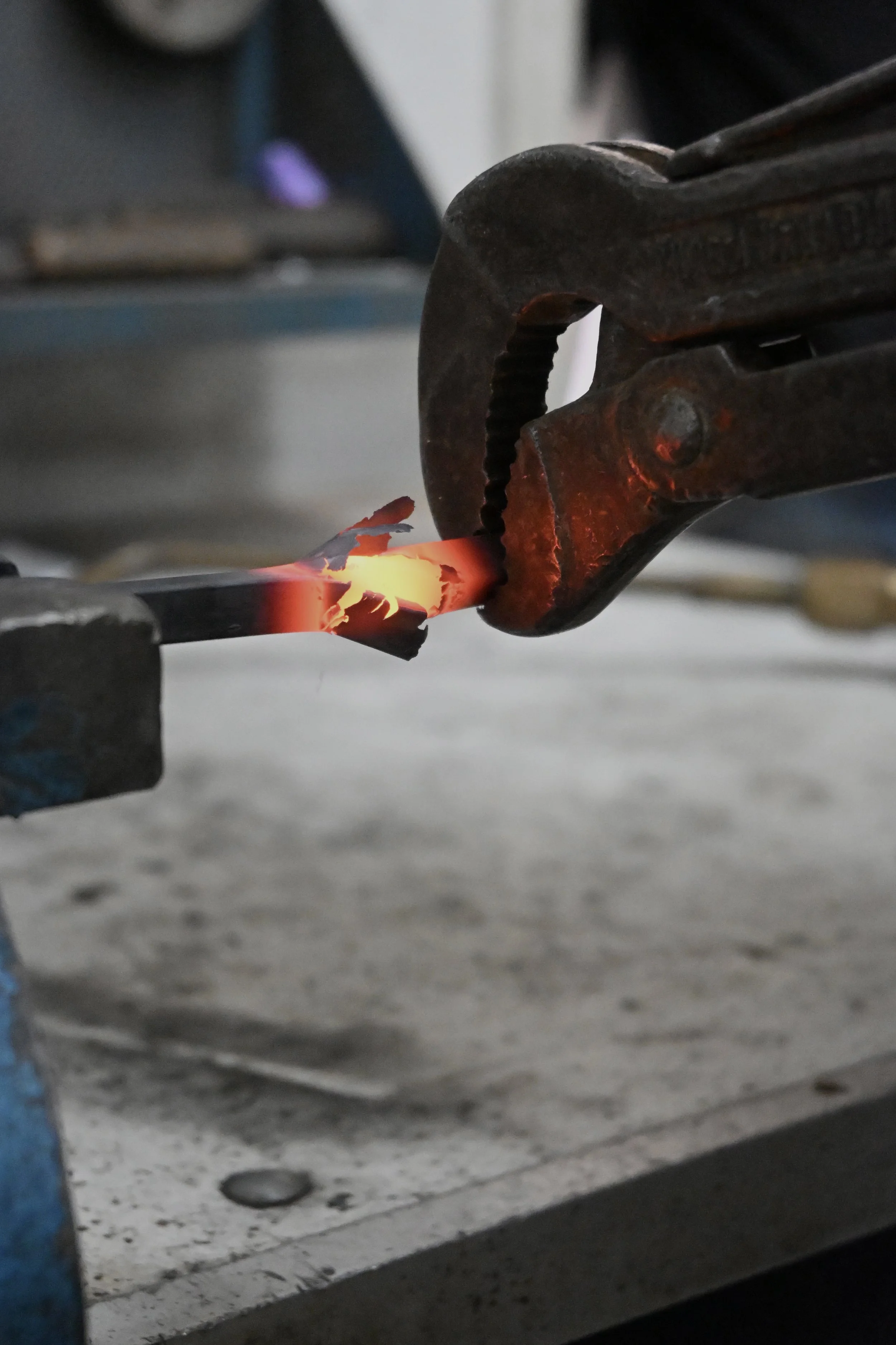 Un fabbro utilizza una pinza per piegare un ferro rovente in una fucina.