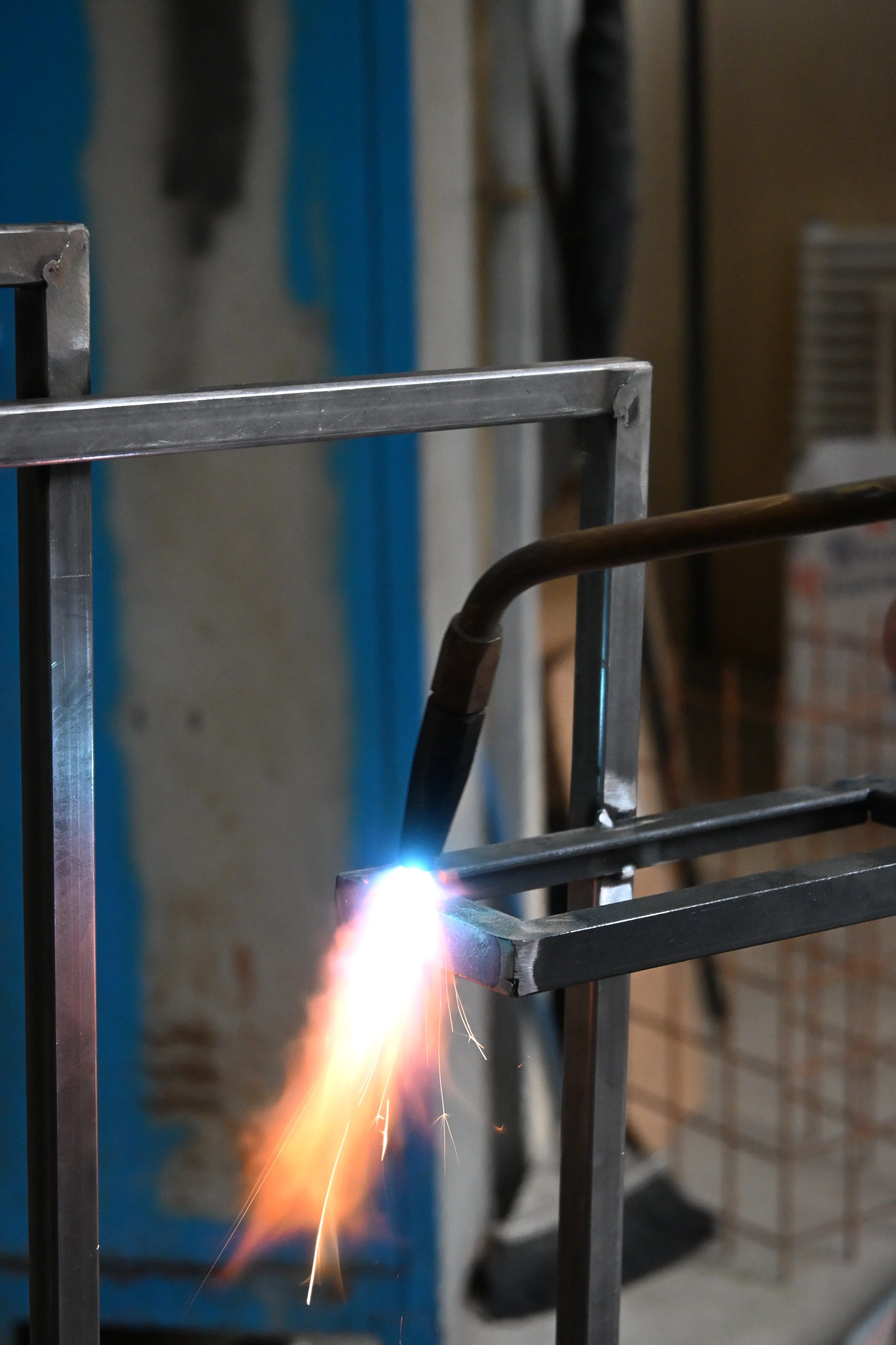 Sede di un soldatore che effettua un saldatura su una struttura in metallo con scintille.