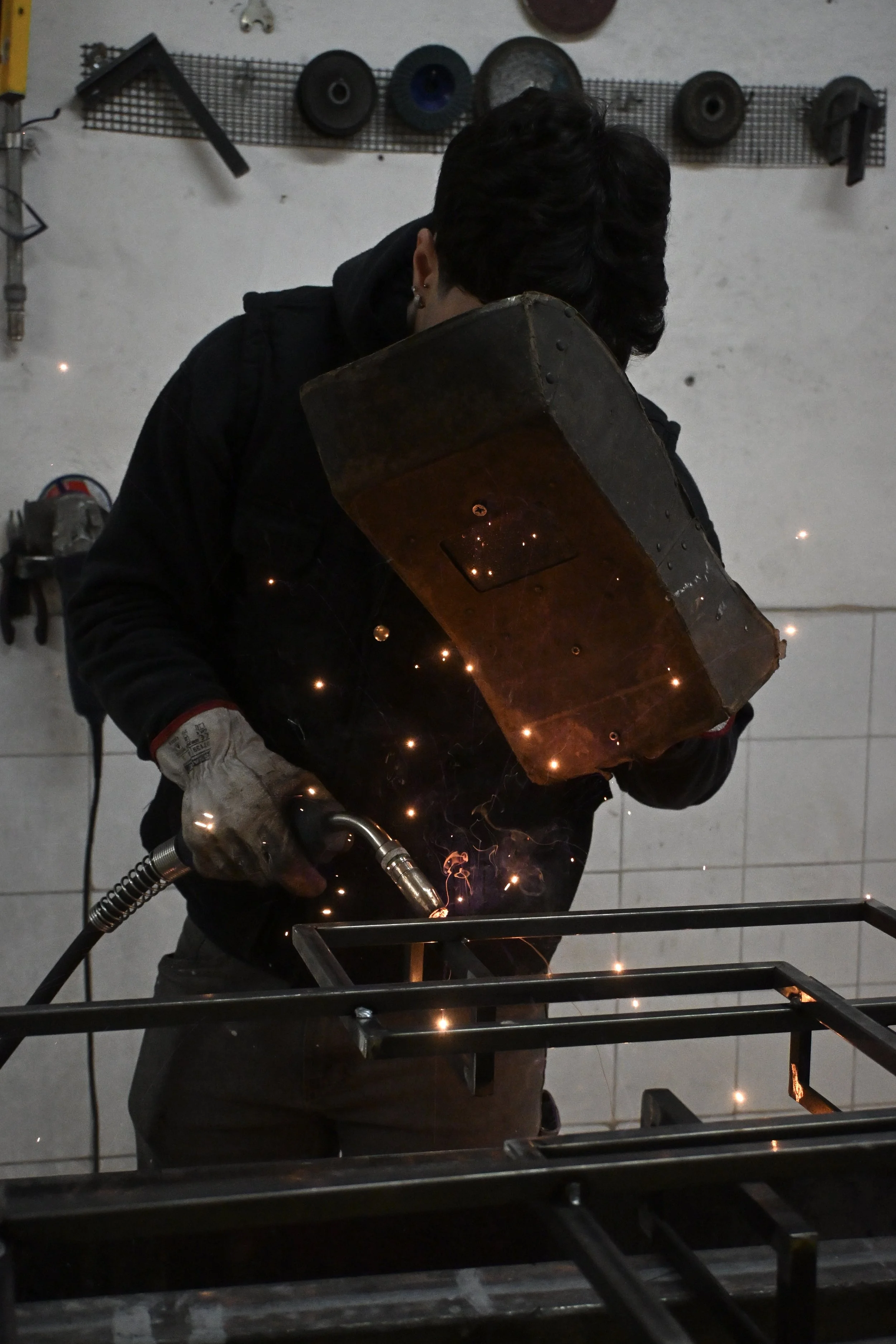 Fabbro al lavoro con saldatrice, scintille visibili, in un'officina.