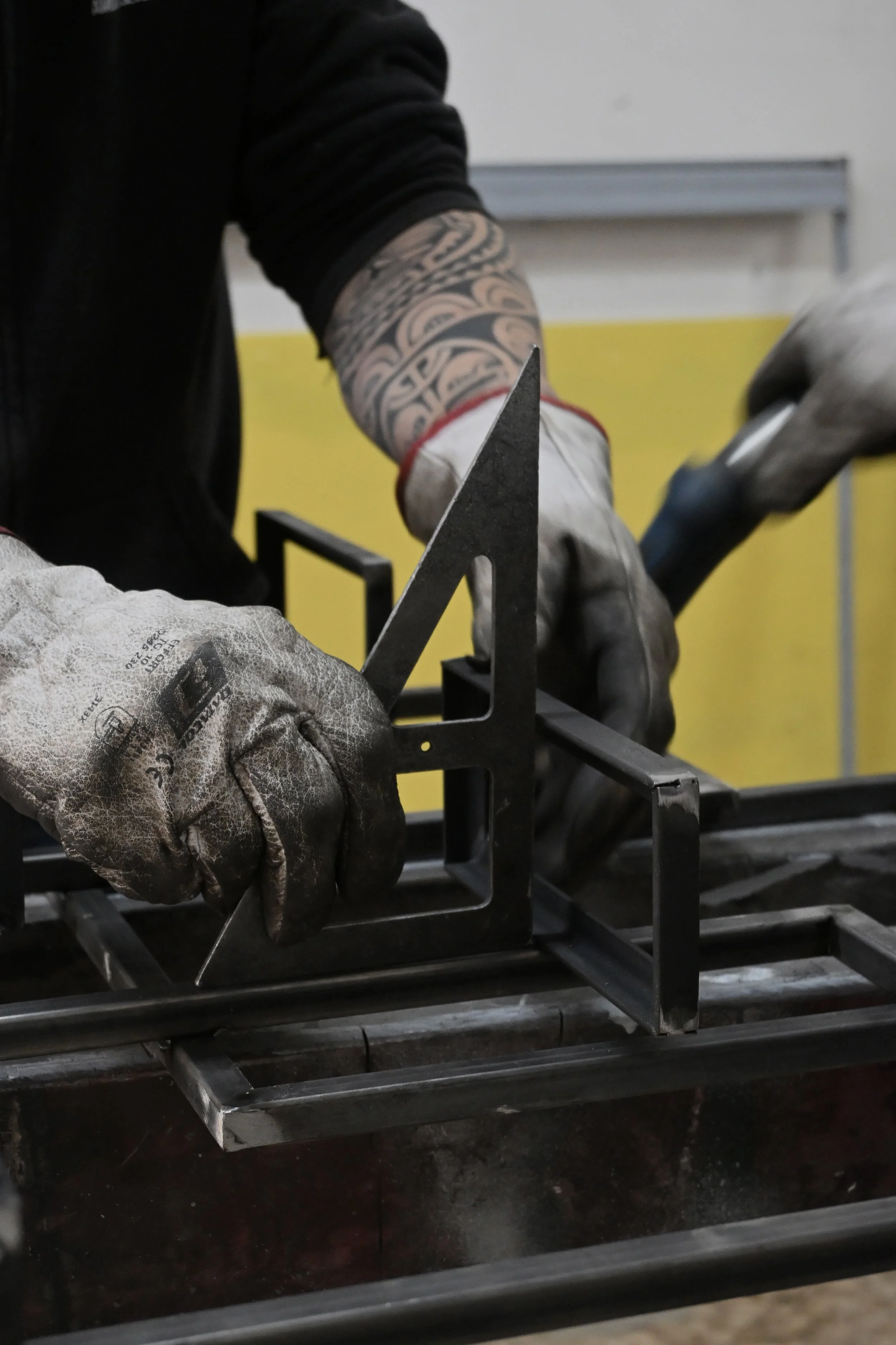 Lavoratore con guanti in impugnatura utilizza strumenti per lavorare il metallo.