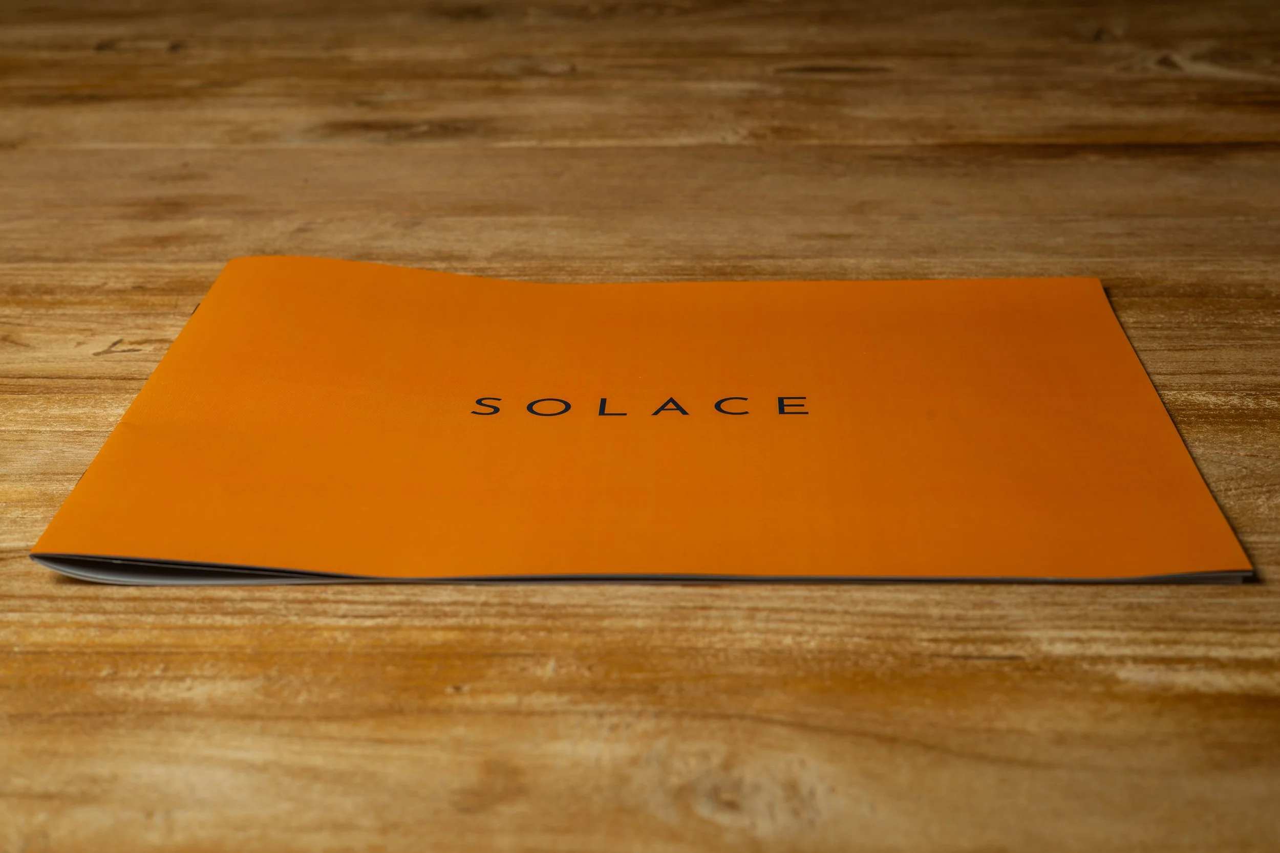 Photo booklet “Solace” on a wooden surface, angled view