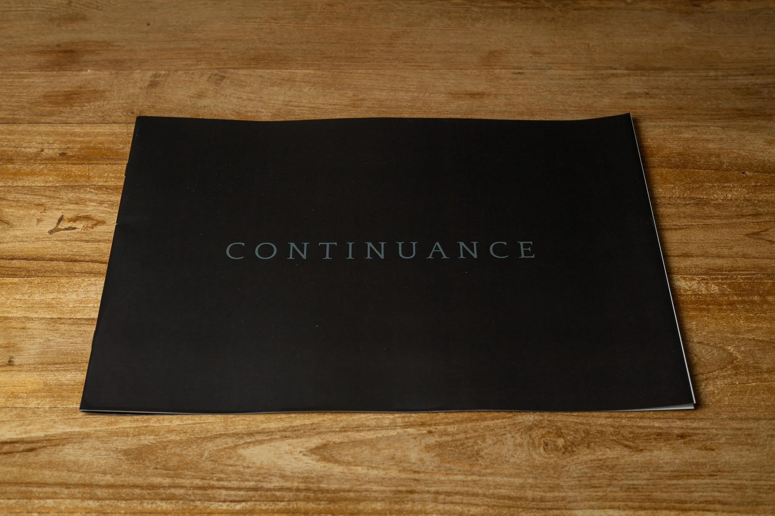 Photo booklet “Continuance” on a wooden surface