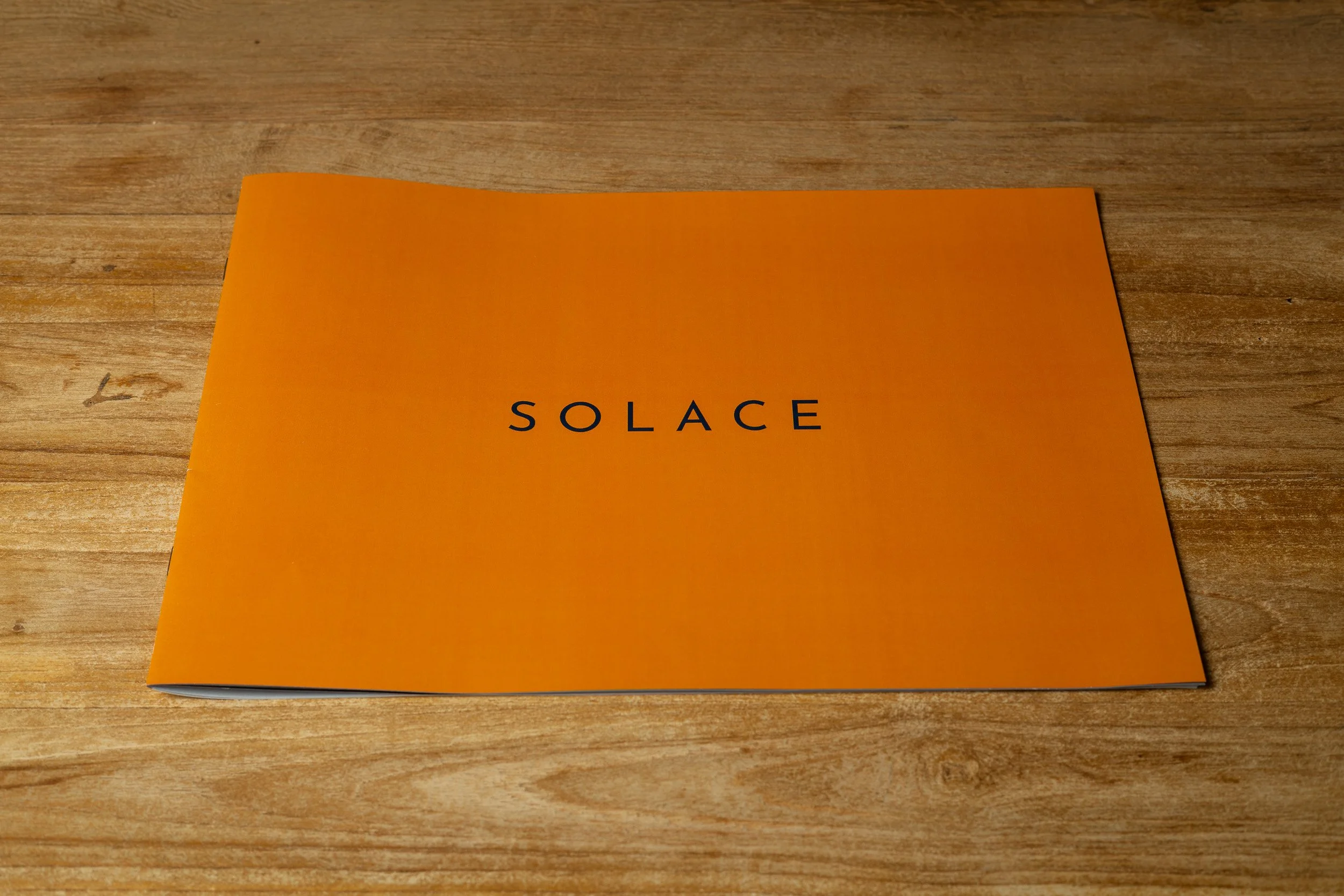 Photo booklet “Solace” on a wooden surface