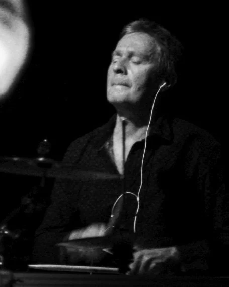 A person with closed eyes, listening to music through earphones, appearing to be emotionally engaged, in a black-and-white photo.